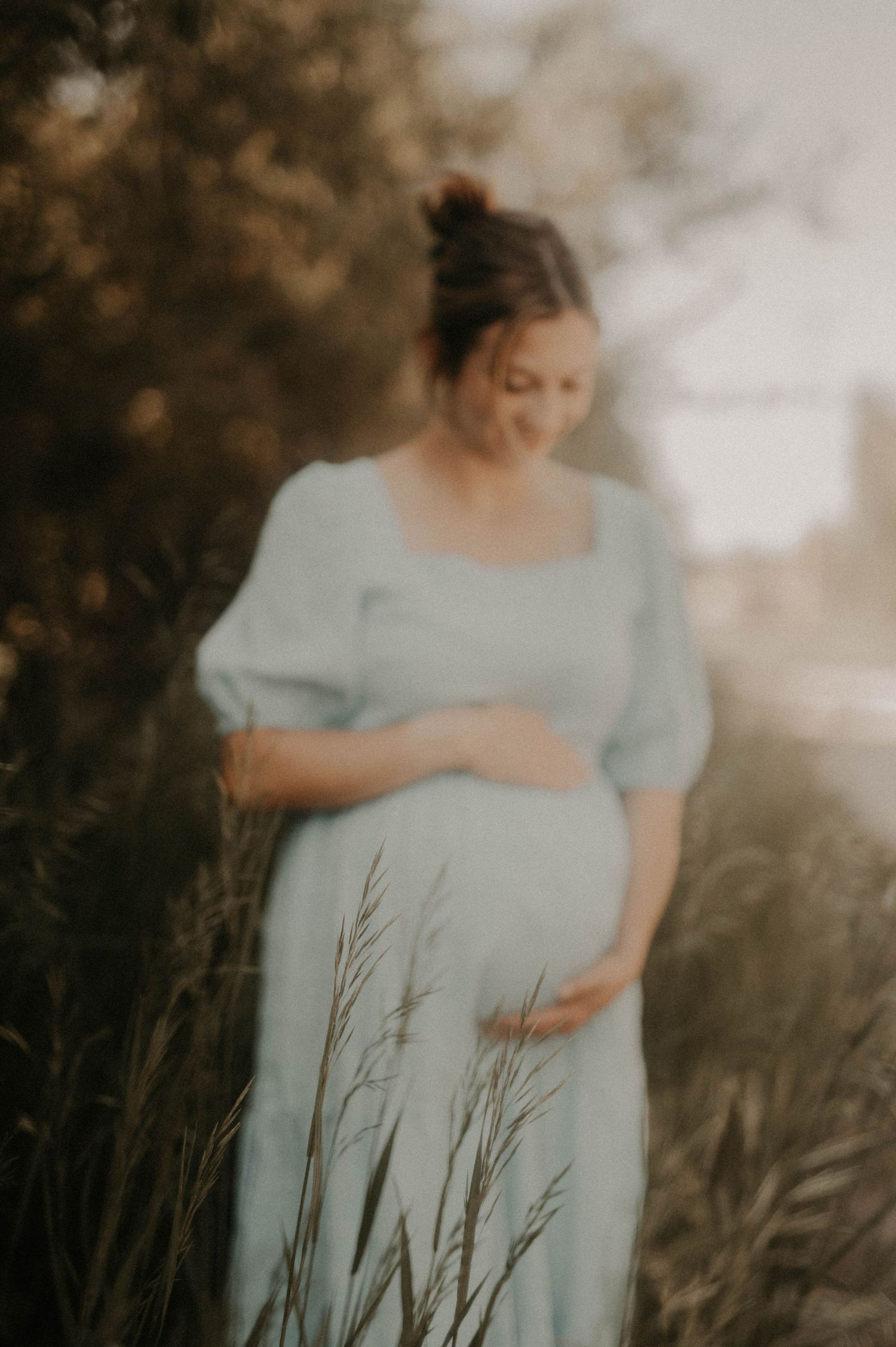A series of ethereal maternity photos in soft mint green dress with tall grasses in the foreground at sunset.