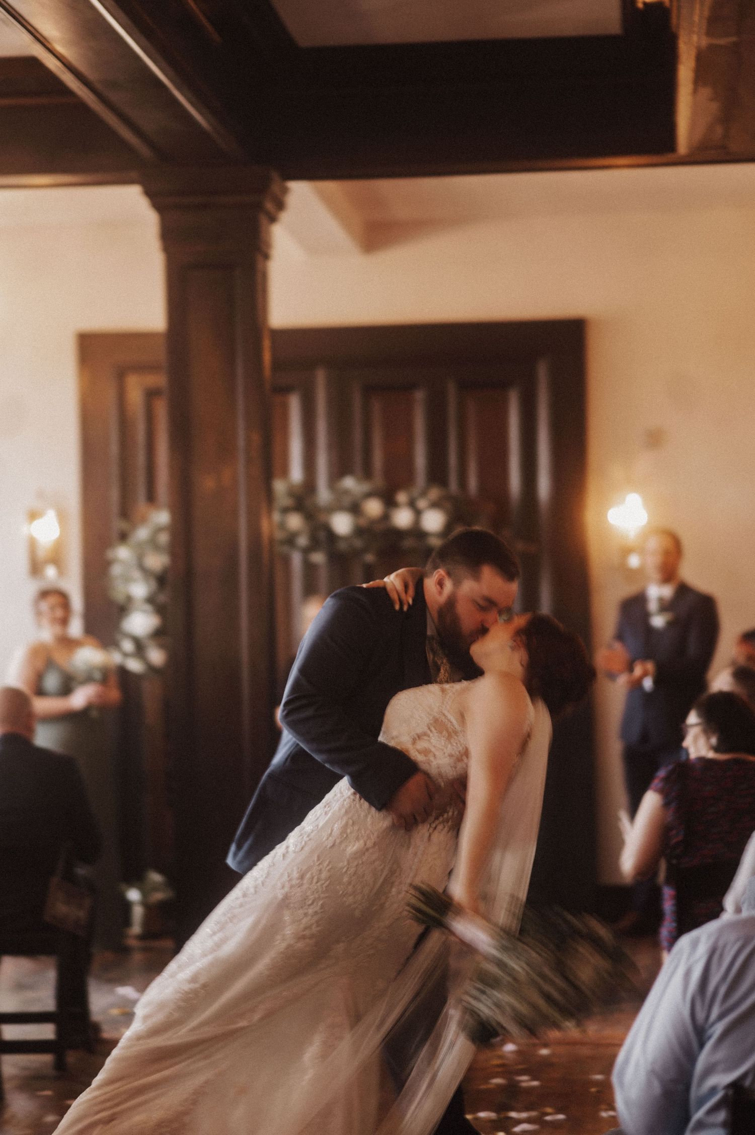 A romantic dip kiss during a wedding reception in a vintage-style venue.