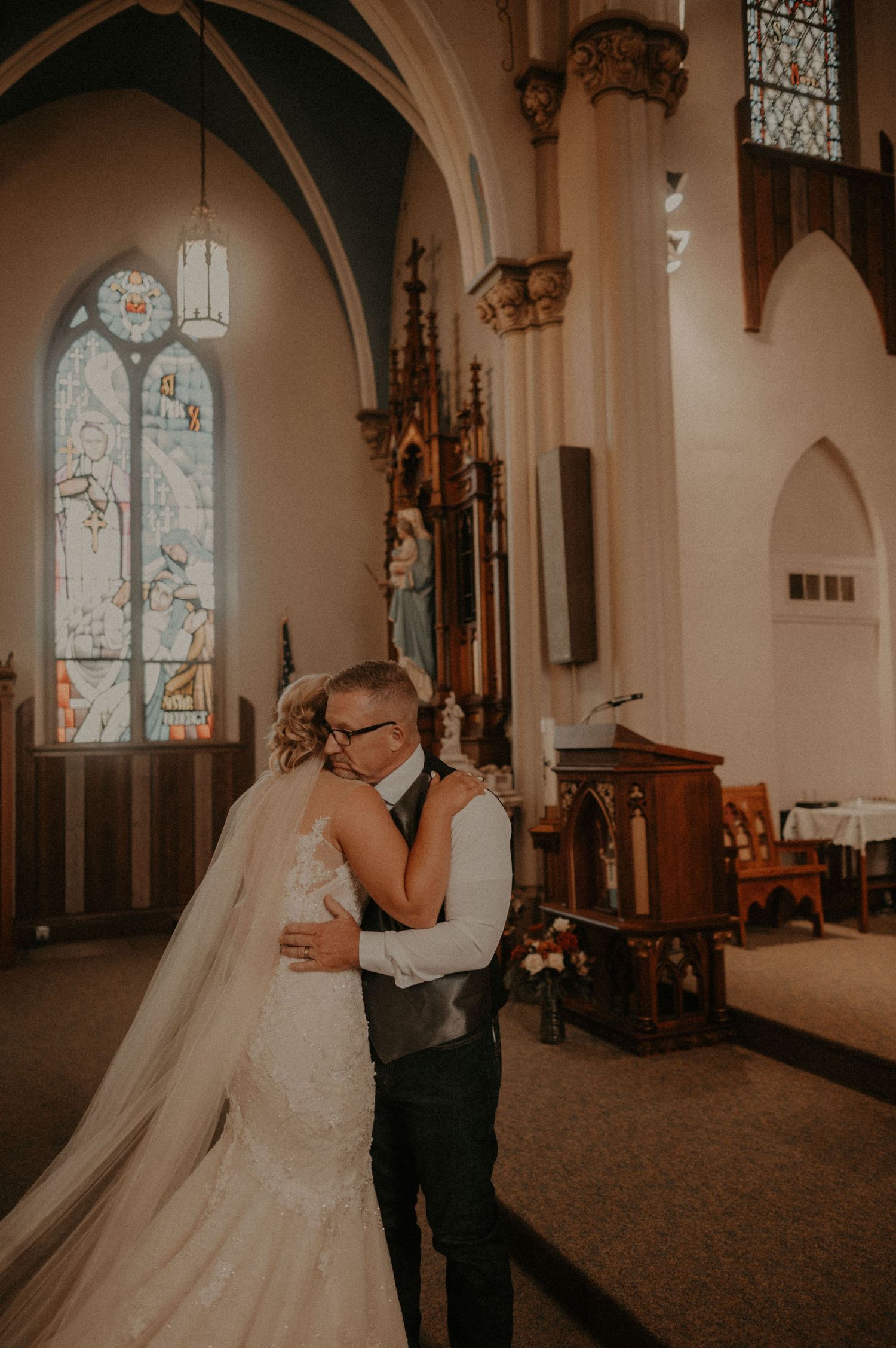 Couple shares an intimate moment during their first look in a church with gothic architecture.