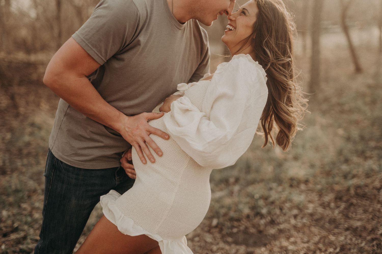 Intimate couple's maternity photos captured in warm sunset lighting among trees.