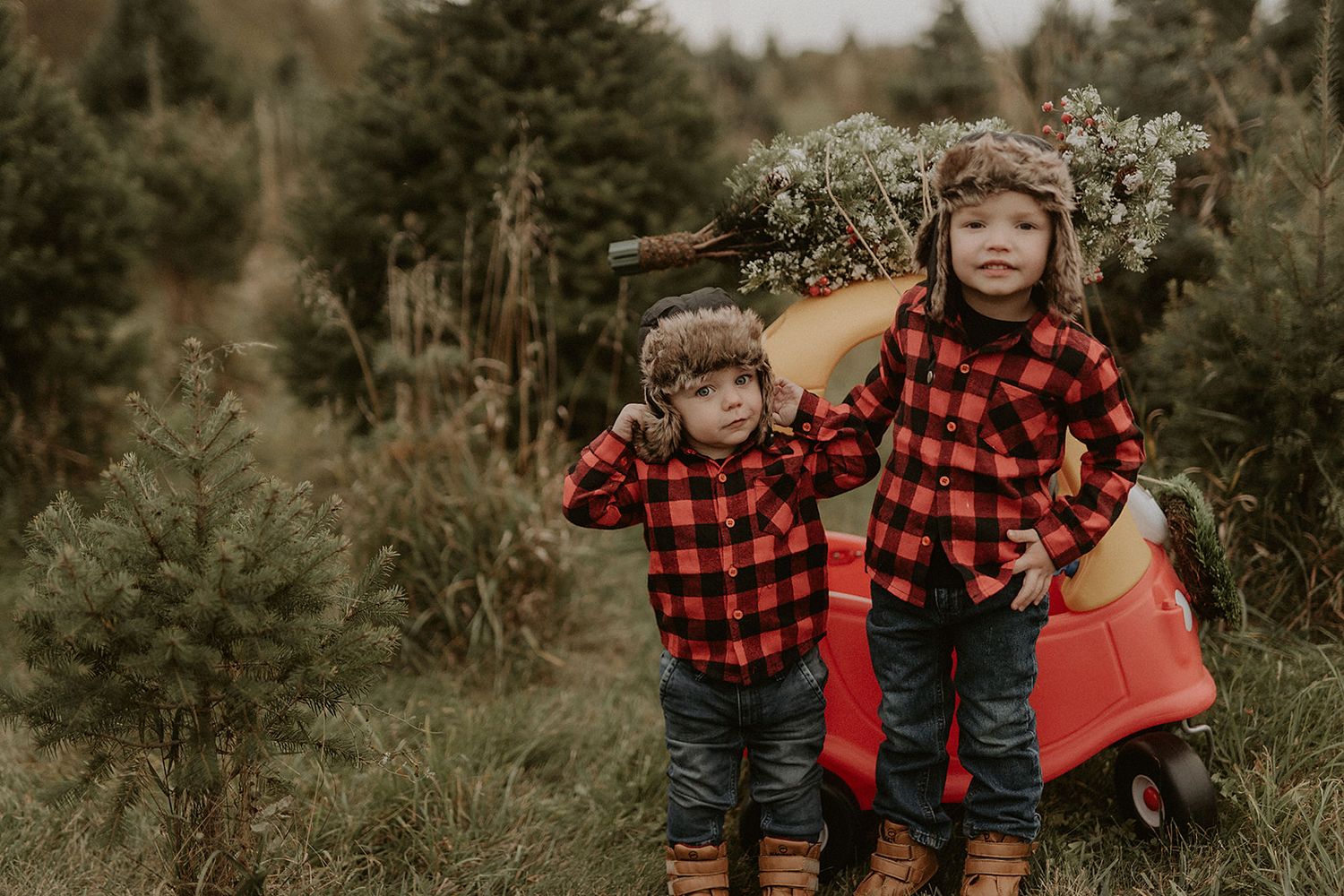 Children in matching red buffalo plaid shirts playing outdoors in a forest setting.