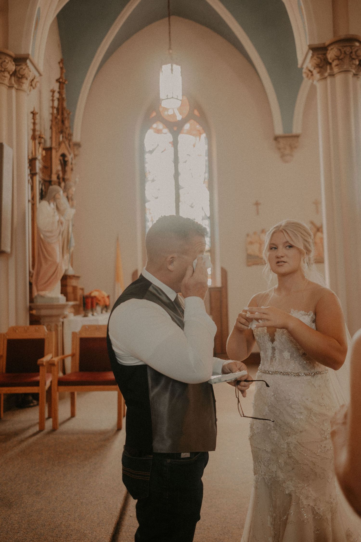 Couple shares emotional first look moment in church sanctuary with natural lighting.