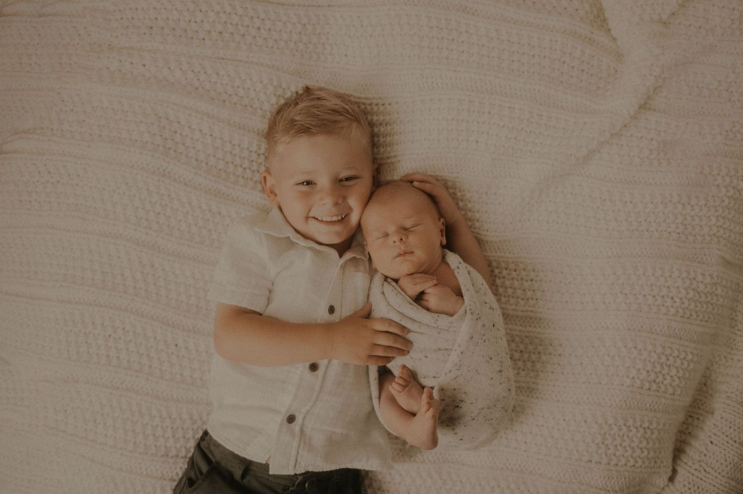 Newborn baby photography session on white textured blanket with soft natural lighting.