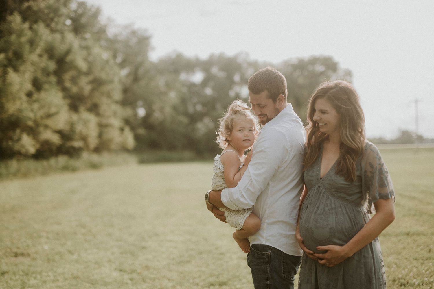 Family enjoying a tender moment together in a sunlit meadow during golden hour.