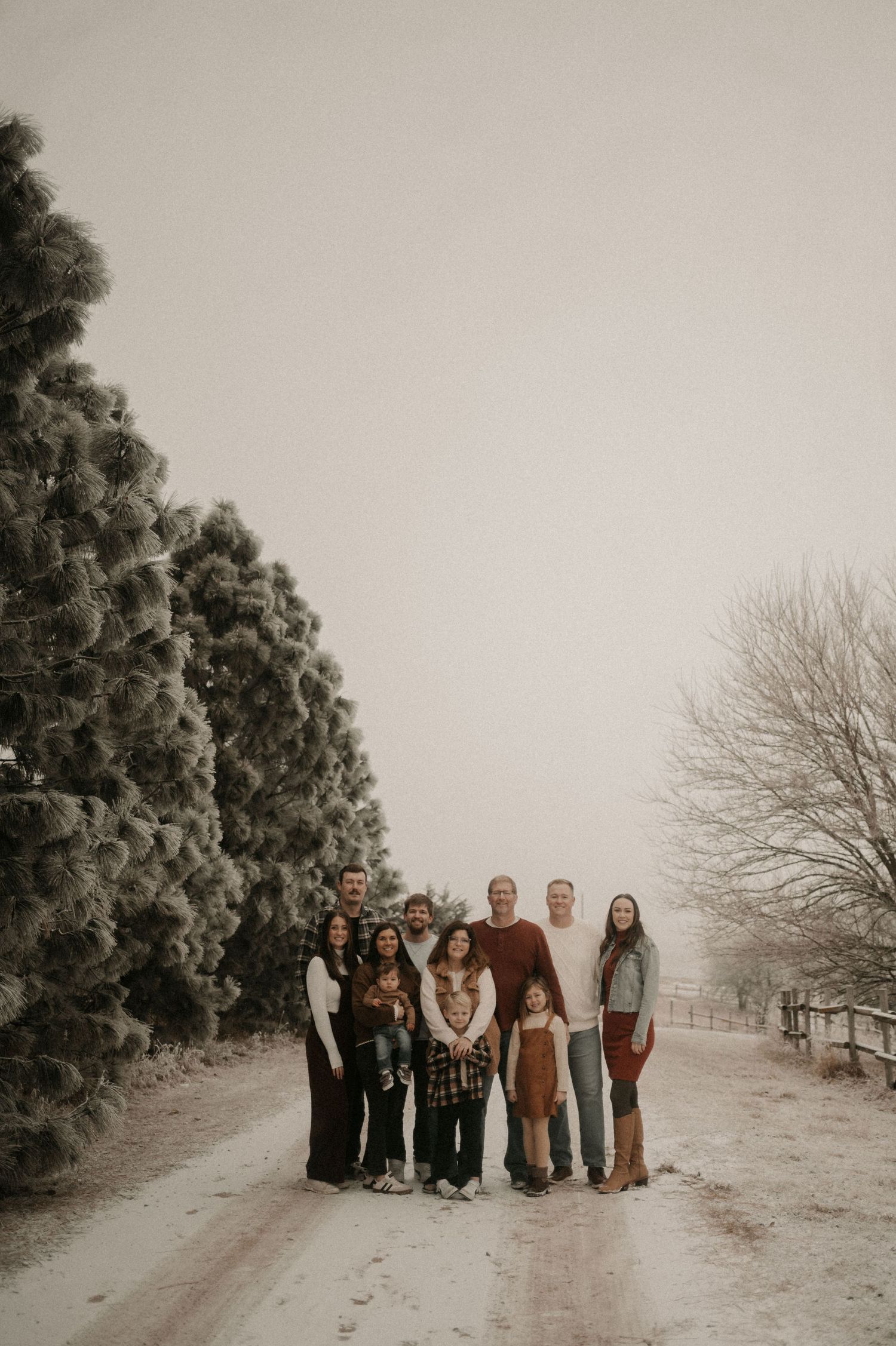 A group of people standing together on a snowy winter path with evergreen trees in the background.