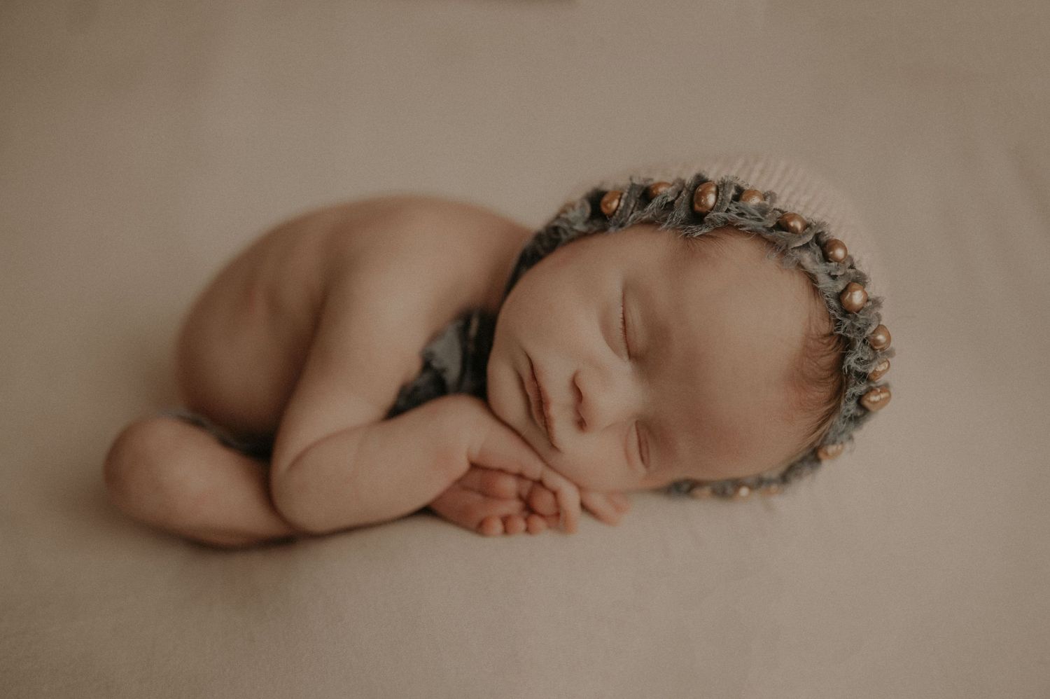 Sleeping newborn baby wearing floral crown in minimalist portrait.