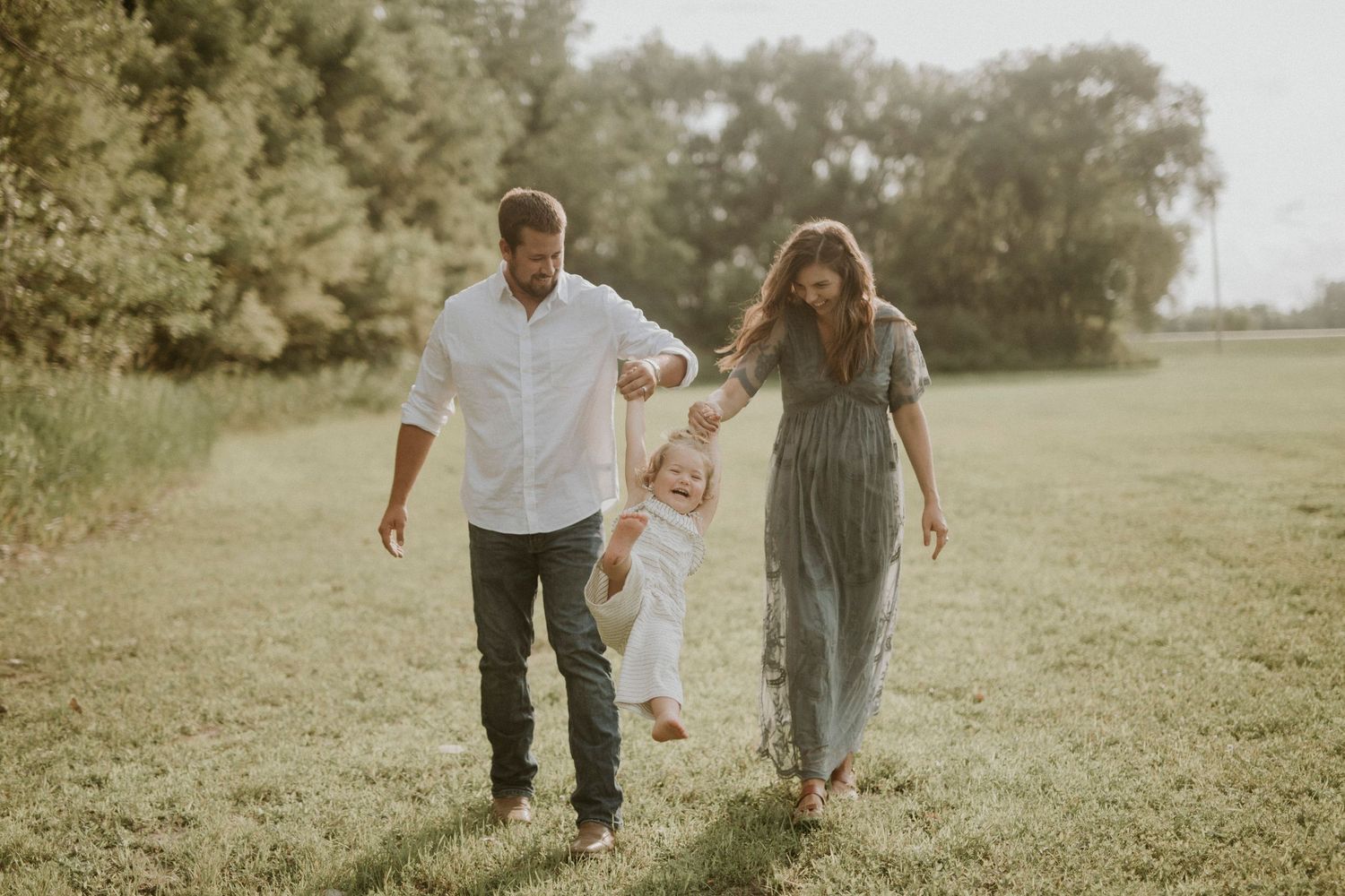 Family walking together and playing in a grassy field on a sunny summer afternoon.