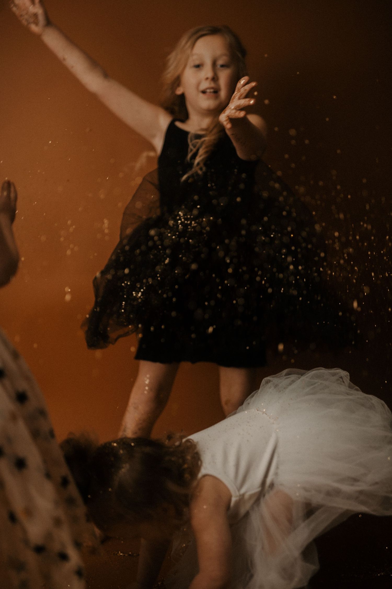 Young dancers in contrasting black and white dresses leap and twirl with glitter sparkling through the air.