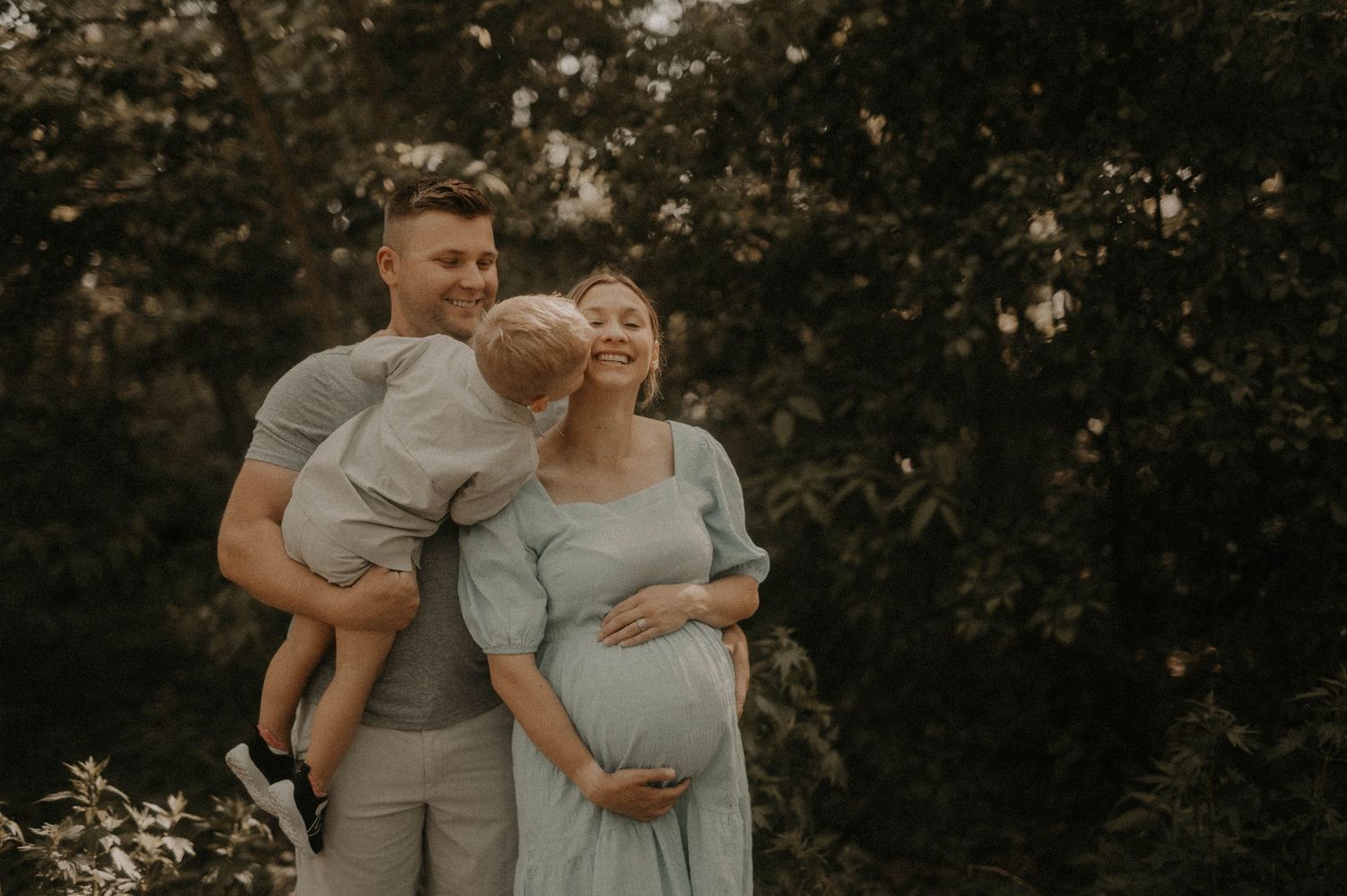 Couple in matching gray outfits embraces tenderly during outdoor photo session at sunset.