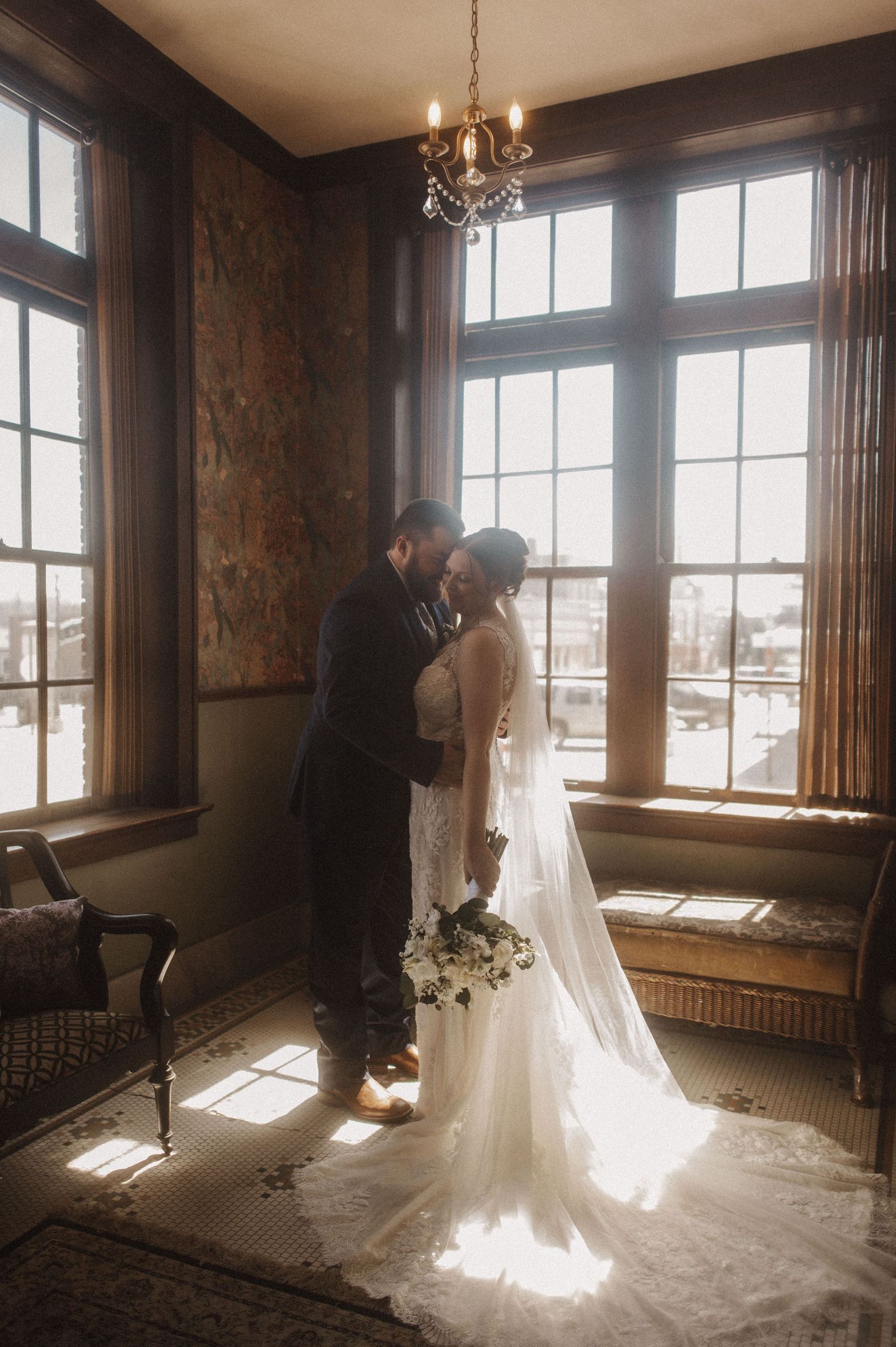 Wedding photography session in an ornate room with dramatic lighting and flowing veil.