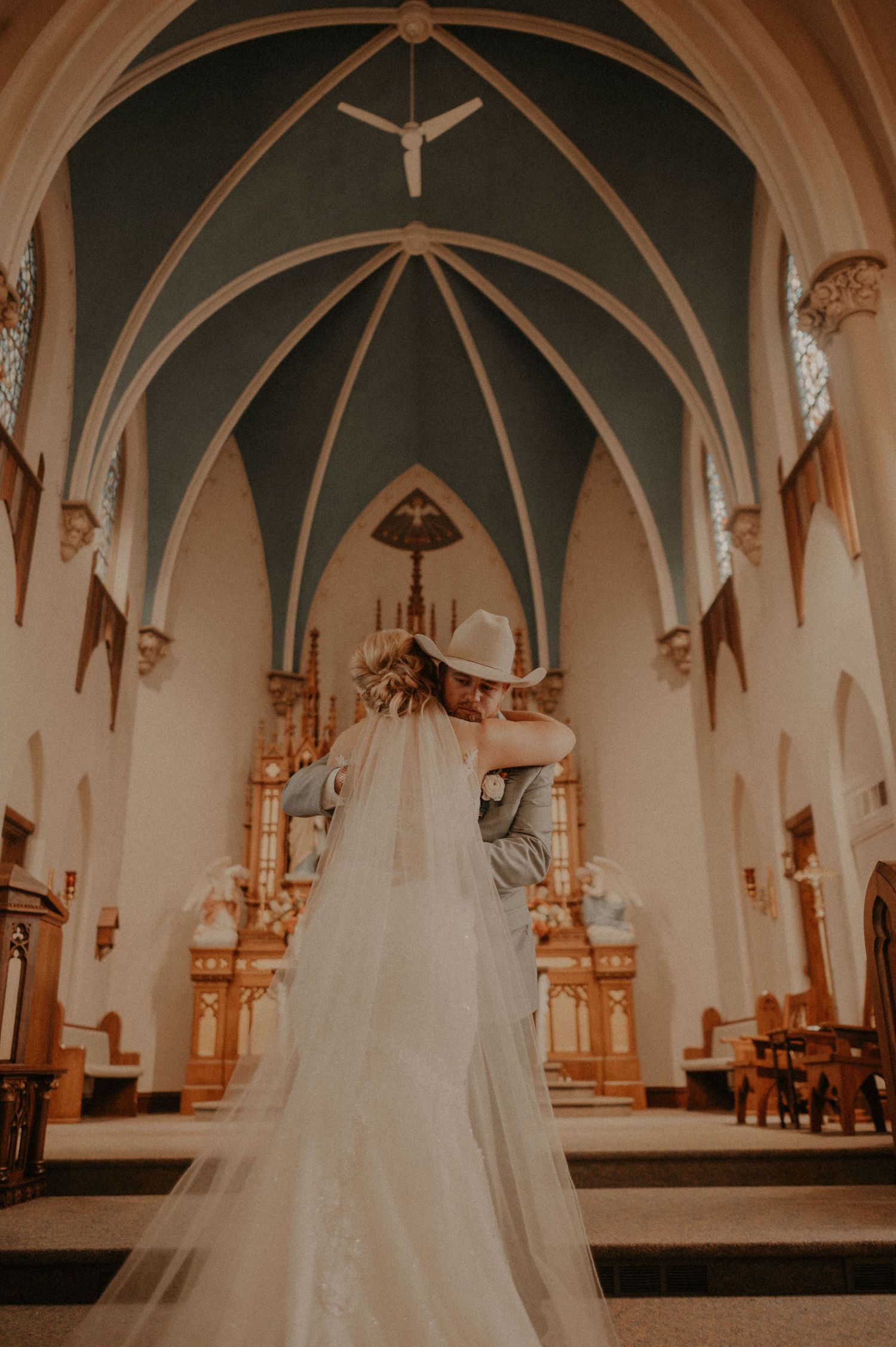 Dramatic cathedral interior with vaulted ceiling and flowing white wedding dress in foreground.