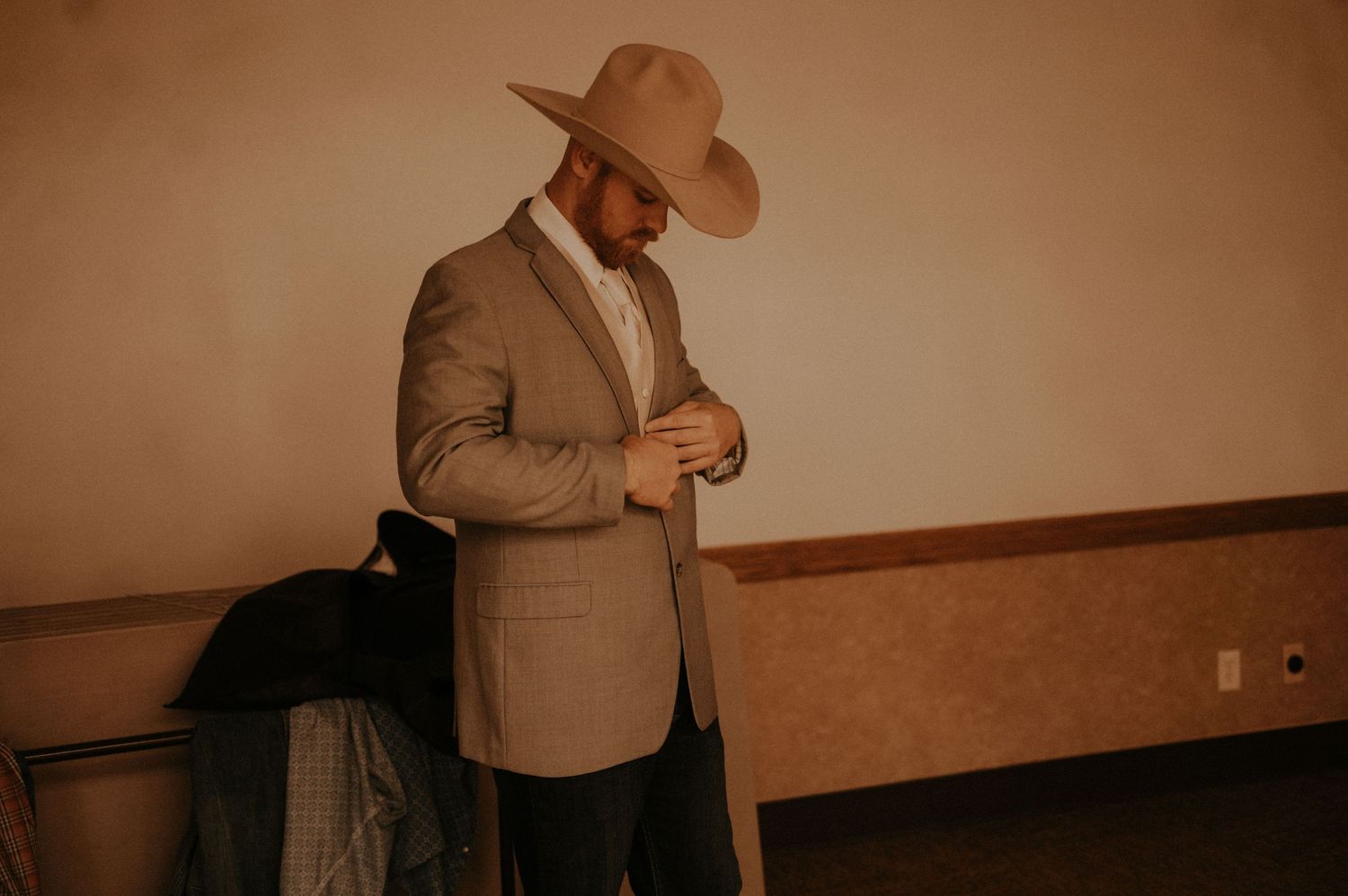 People in western attire and cowboy hats gathered in an indoor space.