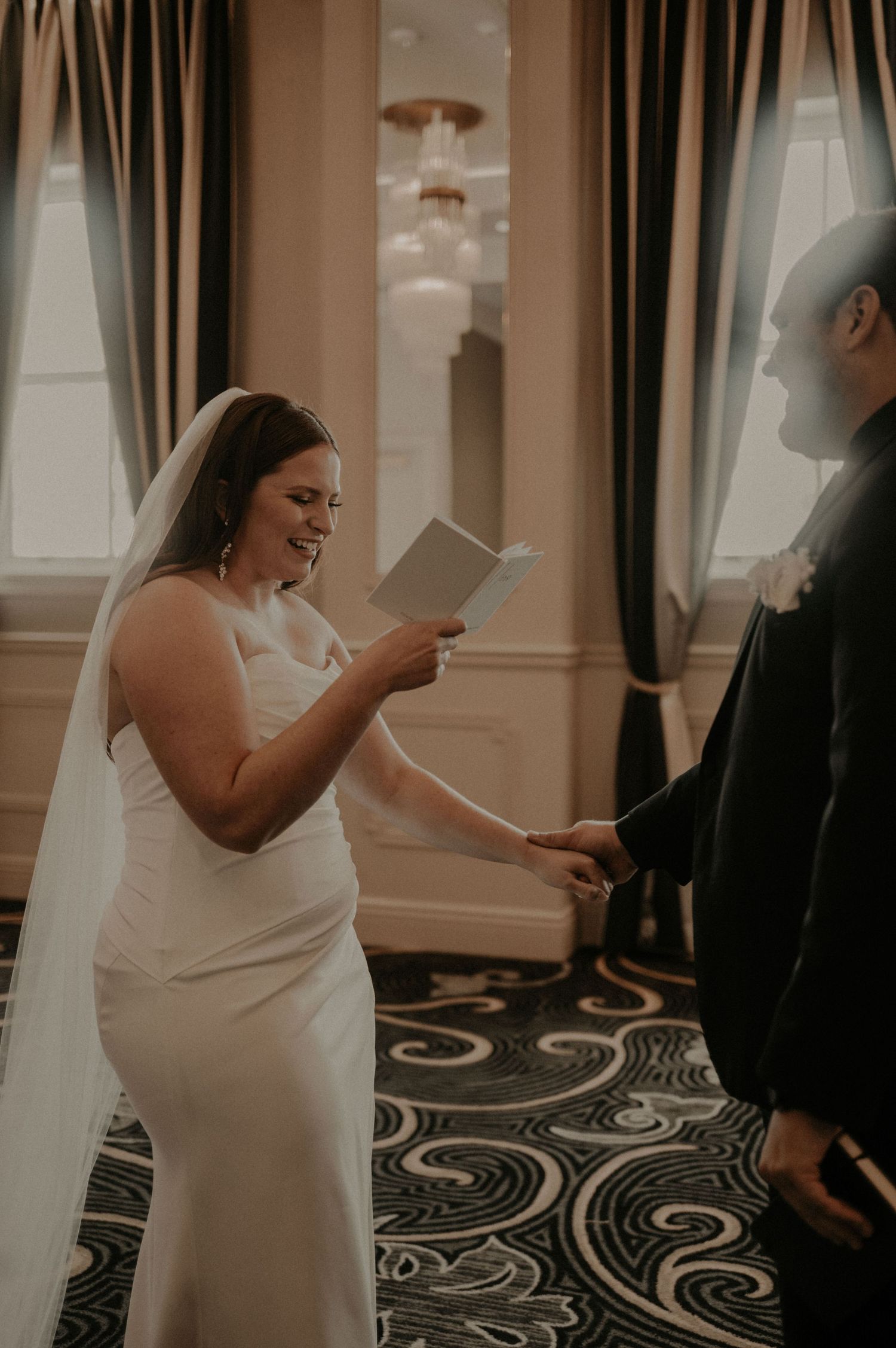 A couple shares a joyful moment during their first dance in an elegant ballroom.