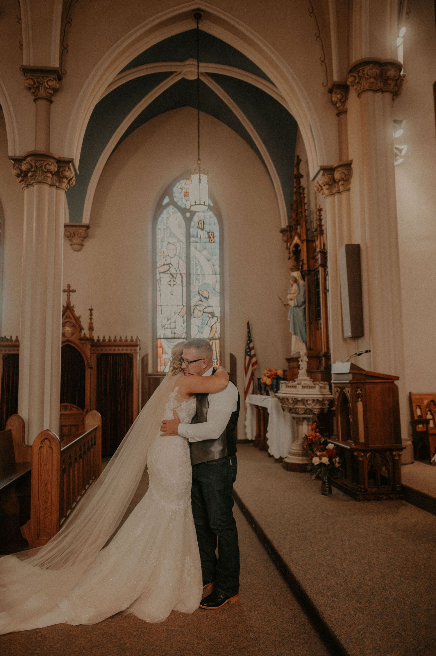 A romantic first dance moment captured in a historic church with ornate arches and stained glass windows.