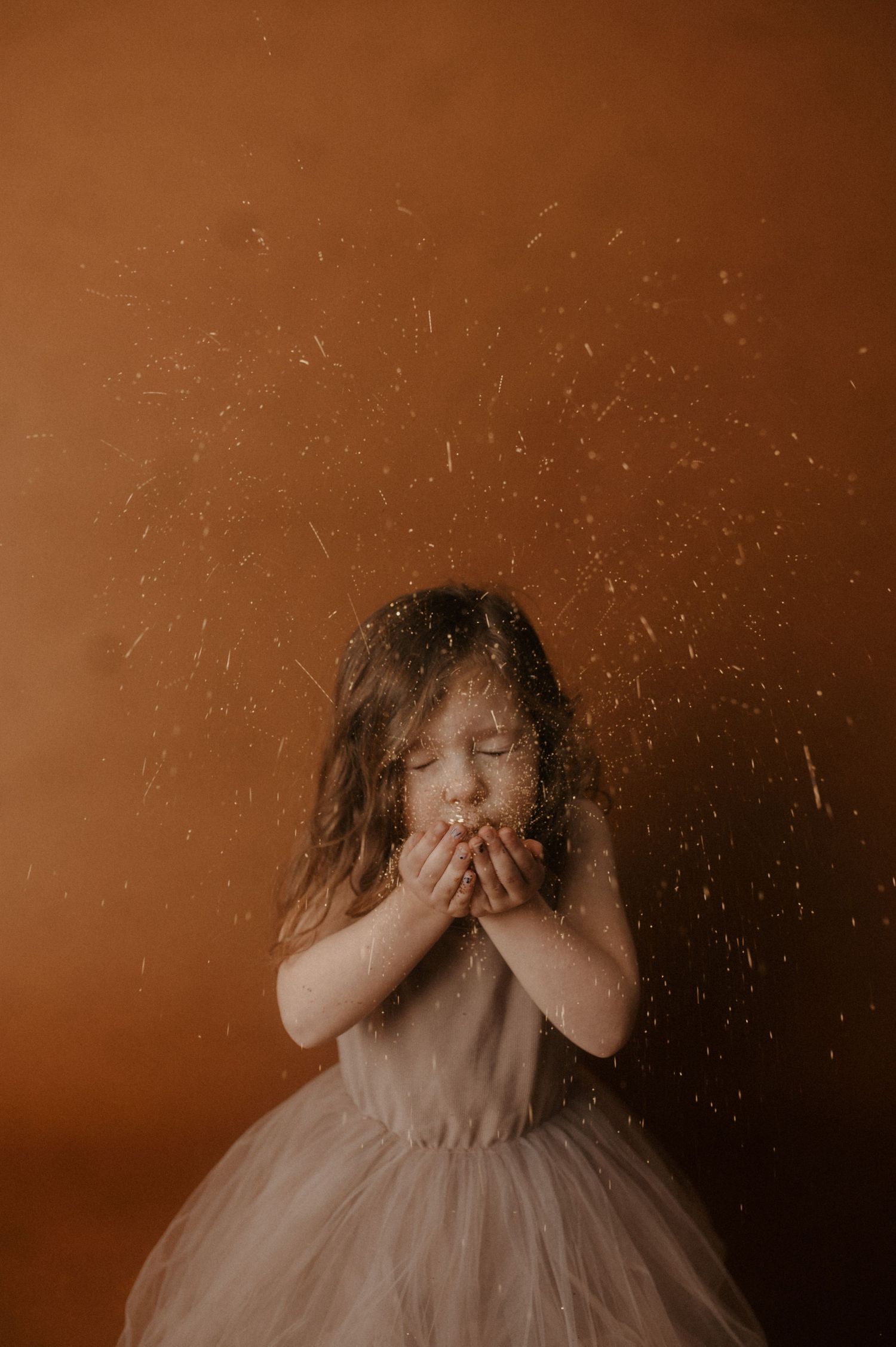 A series of sepia-toned images showing someone in a tulle dress covering their face with their hands.