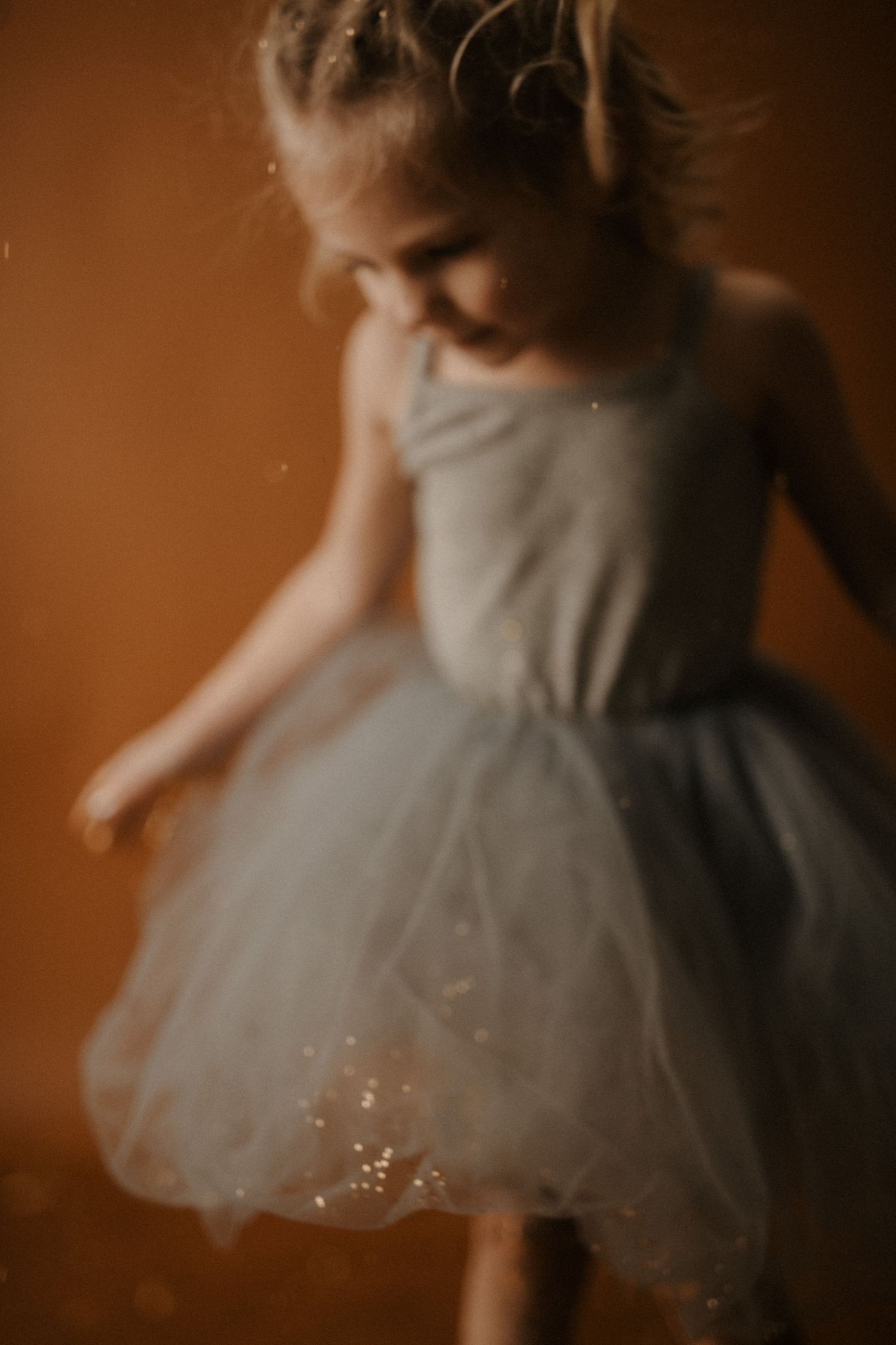 A soft, ethereal series of images showing a white tulle dress twirling in warm sepia-toned lighting.