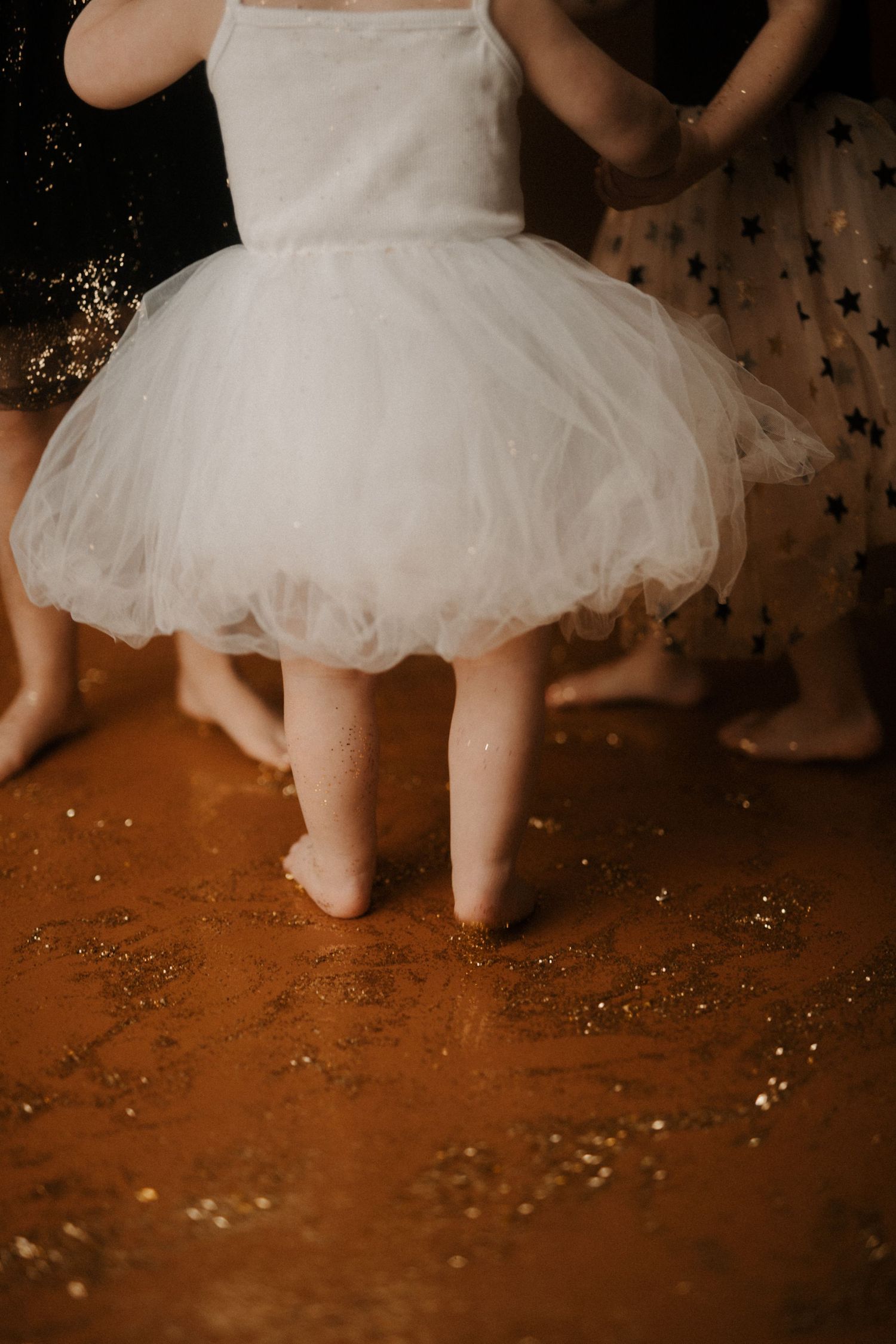 A white tulle tutu dress twirls during a dance performance against a warm-toned background with sparkles.