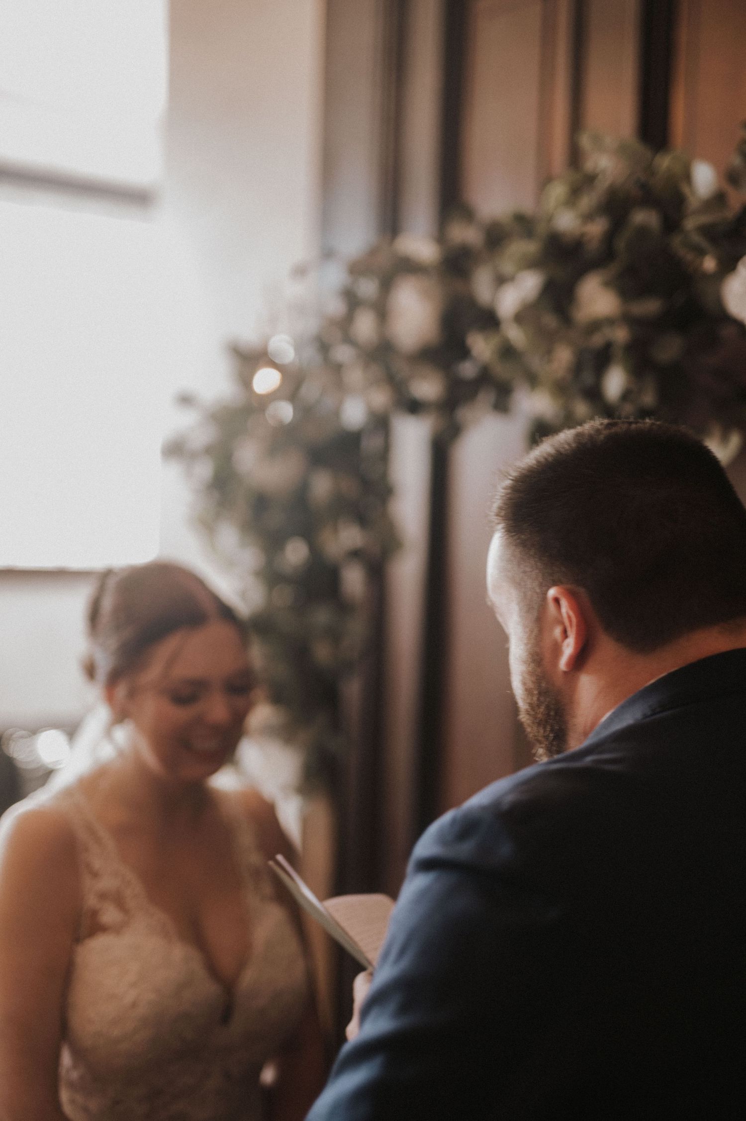 A sunlit wedding ceremony moment beneath a floral arch.