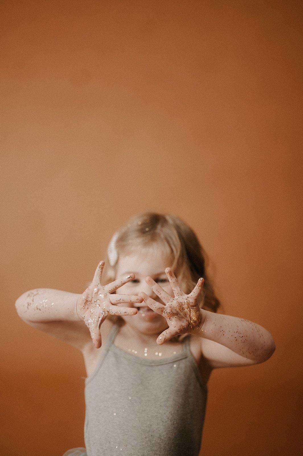 A series of five sequential photos showing hands with glitter covering them against a warm brown background.