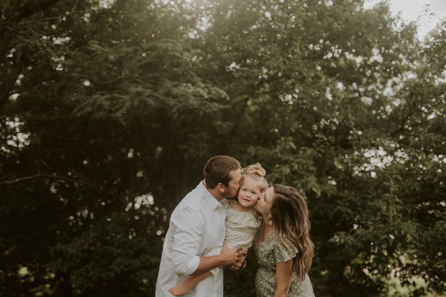 A loving couple shares a tender moment together outdoors with trees in the background during golden hour.
