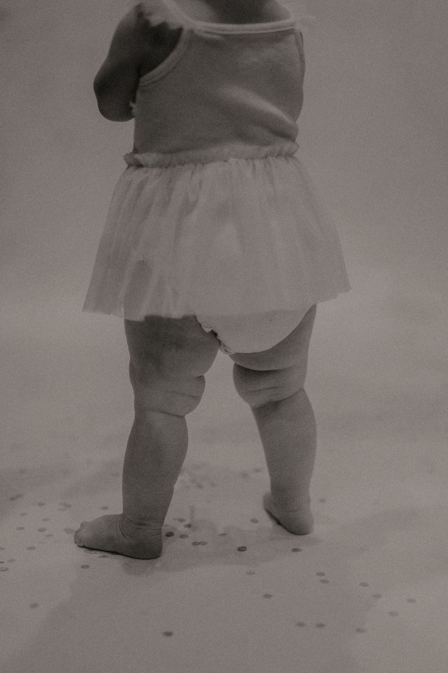 Black and white photograph sequence showing close-up view of baby's legs taking first steps on a textured surface.