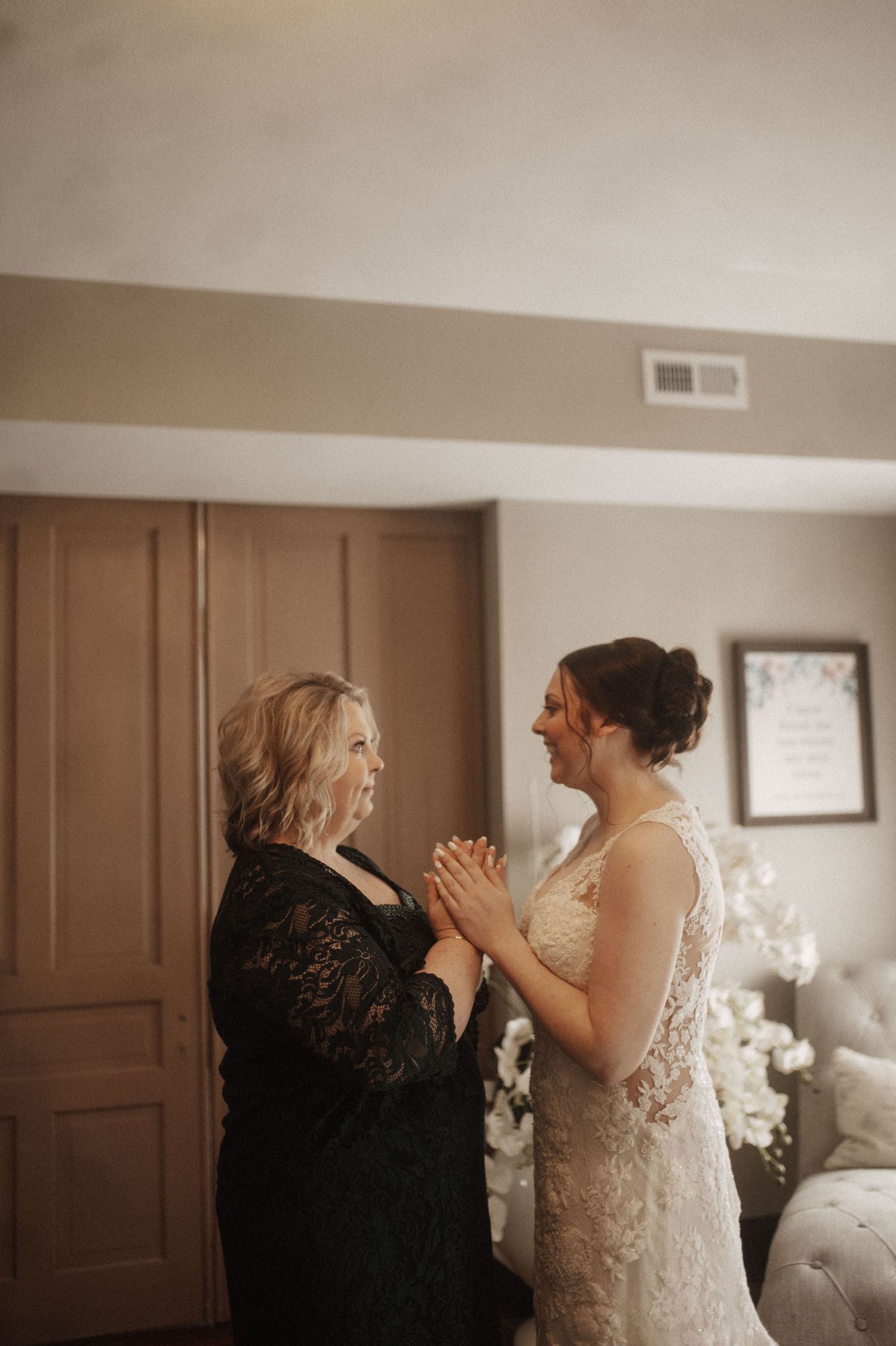Two people share an emotional moment in a room decorated with white flowers and brown wooden panels.