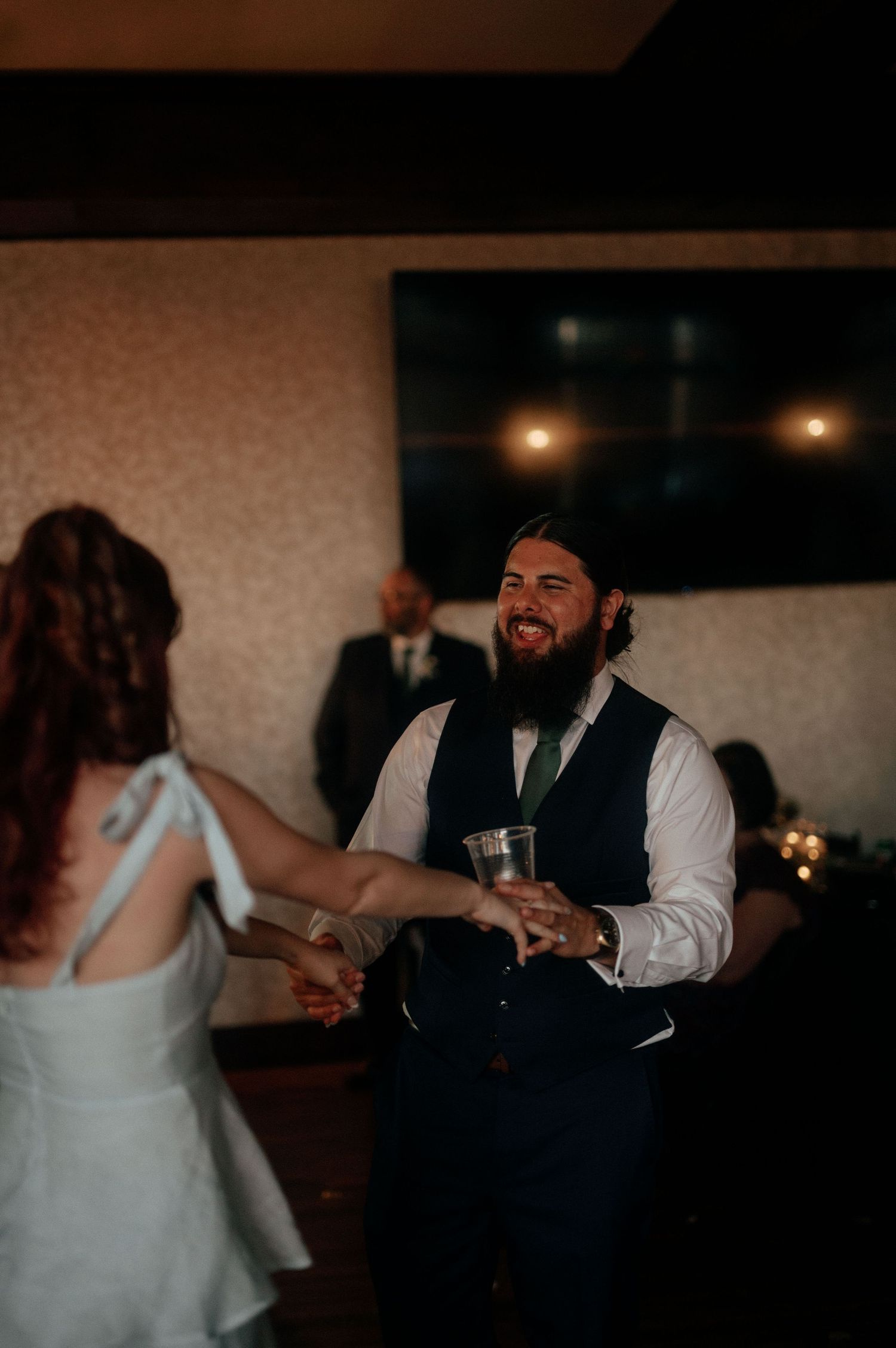 Wedding reception guests dancing and celebrating in a darkened ballroom.