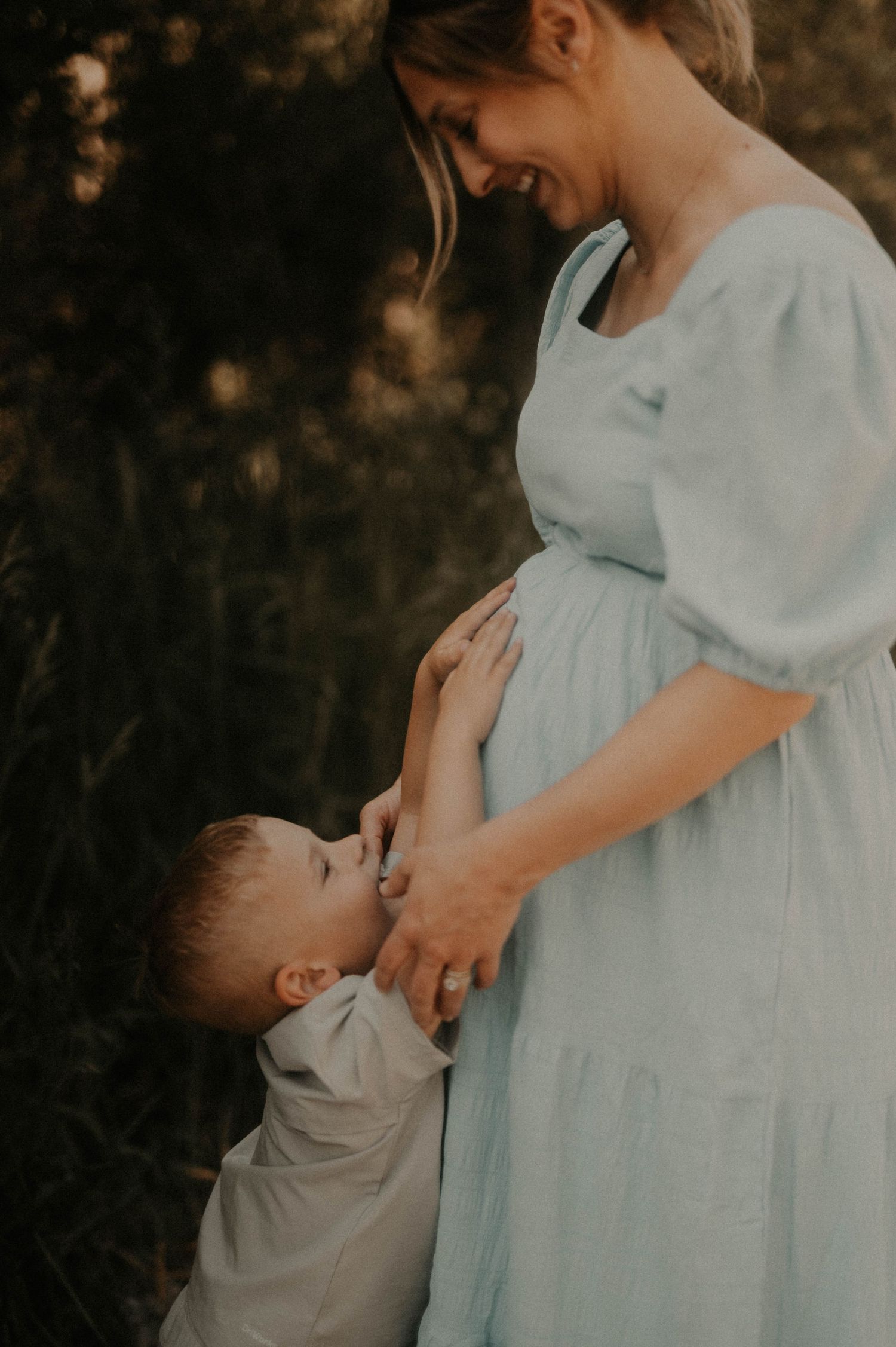 A tender moment between parent and child in soft lighting wearing light blue and white clothing.
