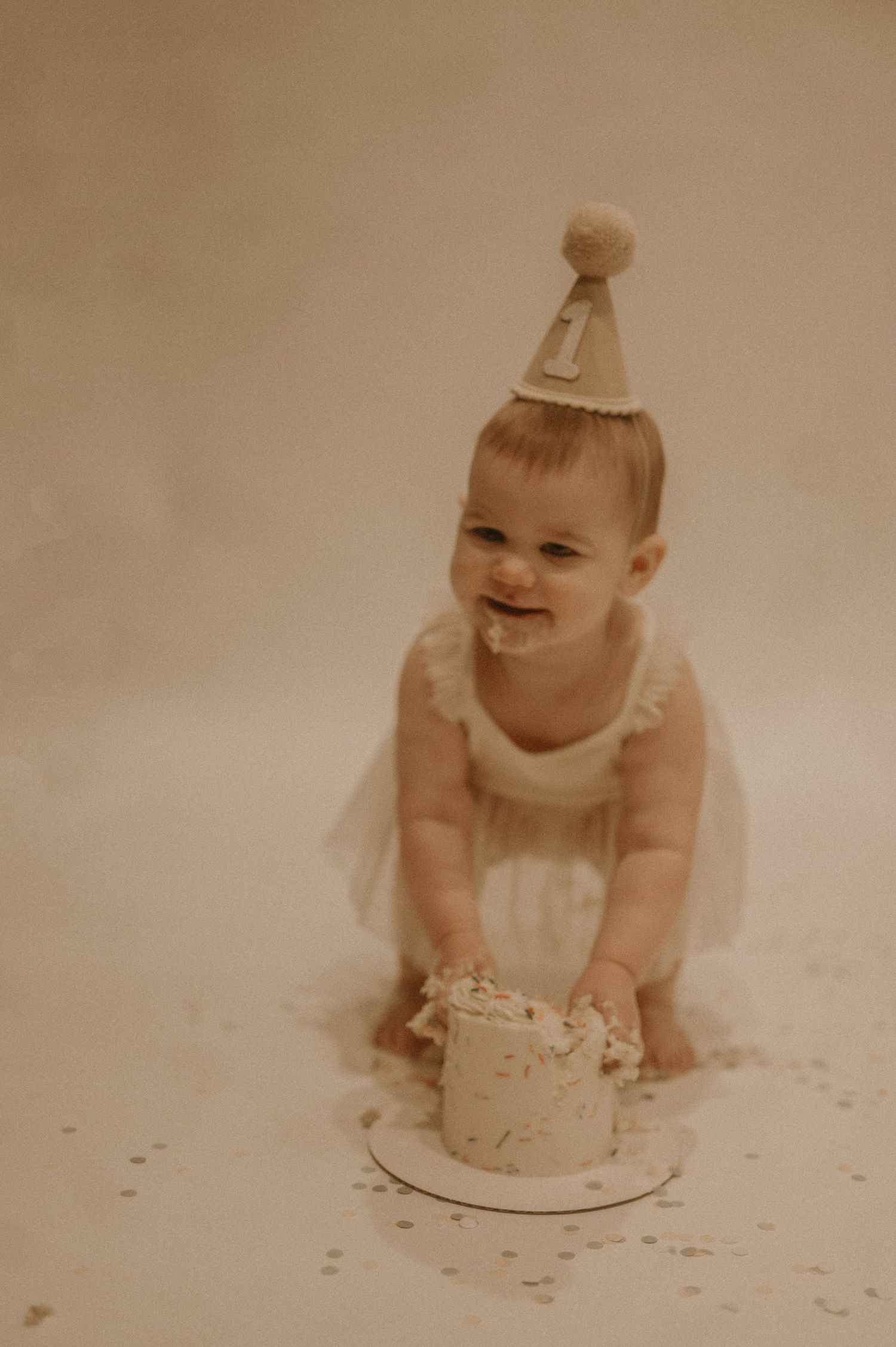 Vintage sepia photo series showing a baby in a party hat examining and smashing their first birthday cake.