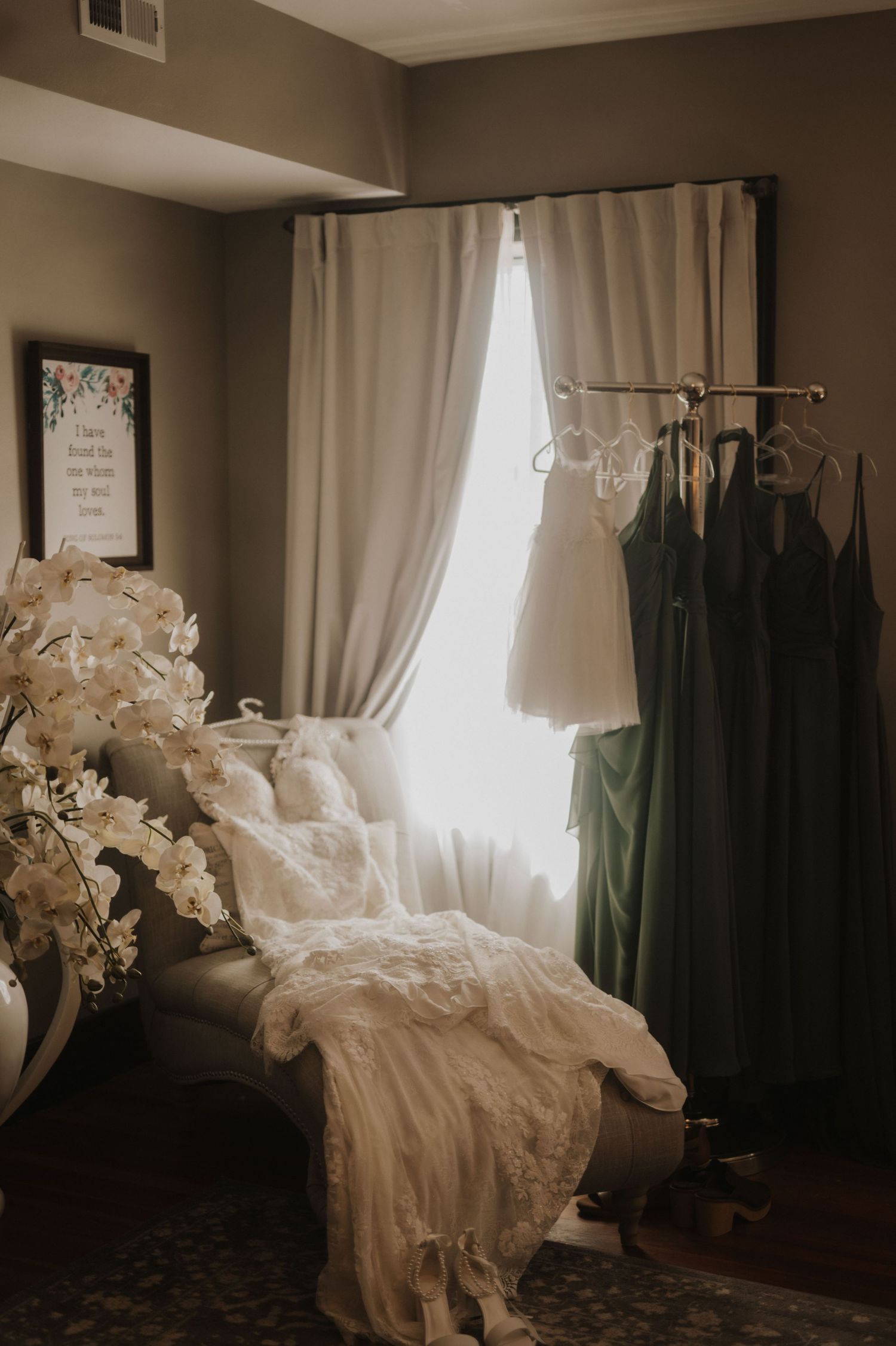 Elegant wedding dress displayed in a room with white curtains and natural lighting.