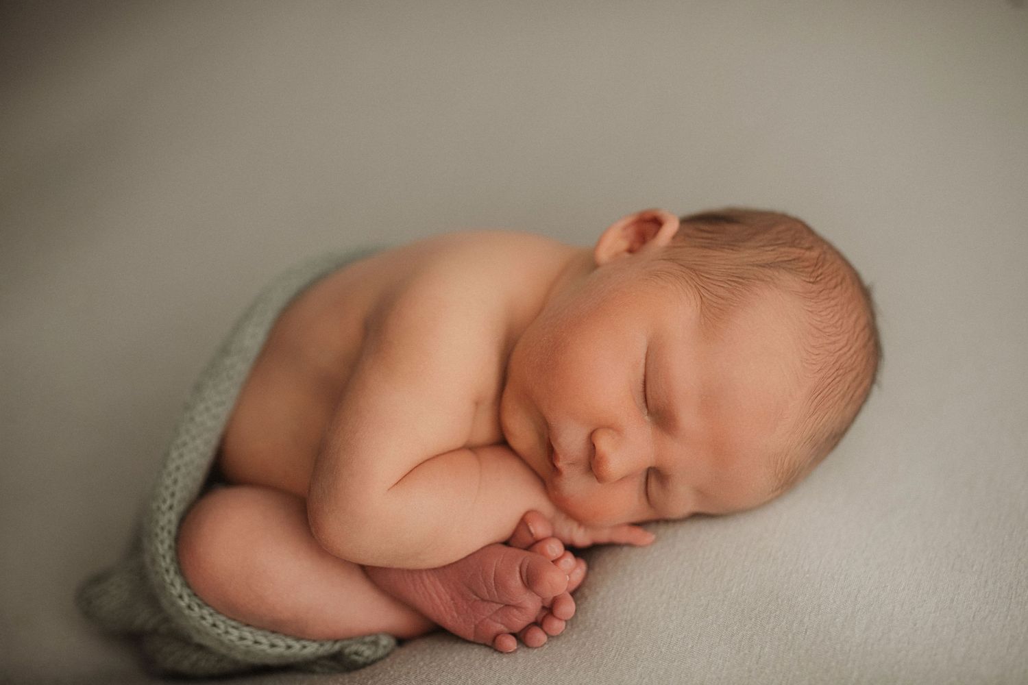 Professional newborn portrait with minimalist gray backdrop and natural posing.