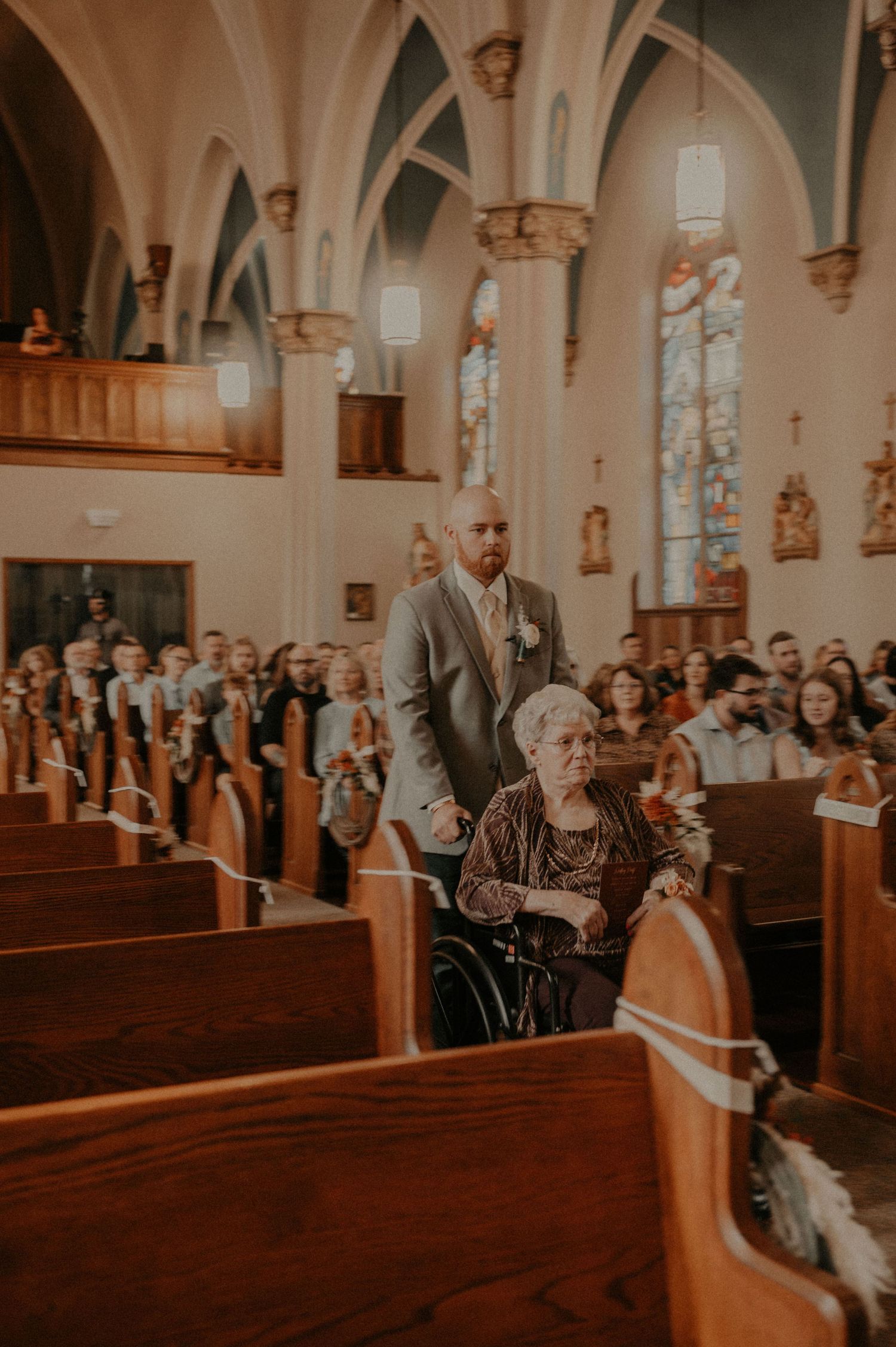 Church wedding ceremony with guests watching from wooden pews under gothic arched ceilings.