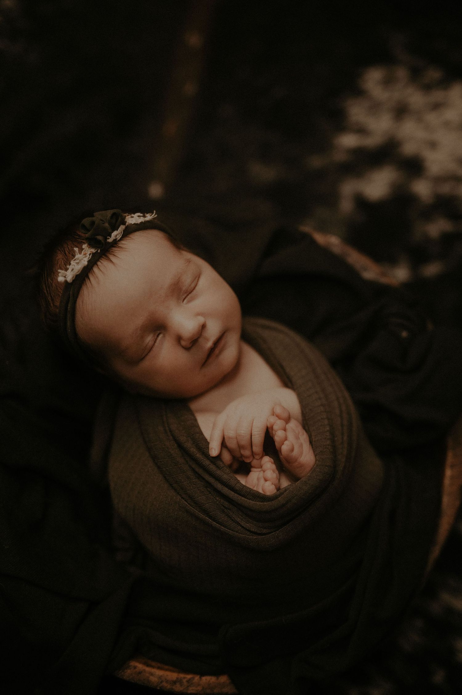 An artistic close-up portrait with deep shadows and intimate composition in sepia tones.