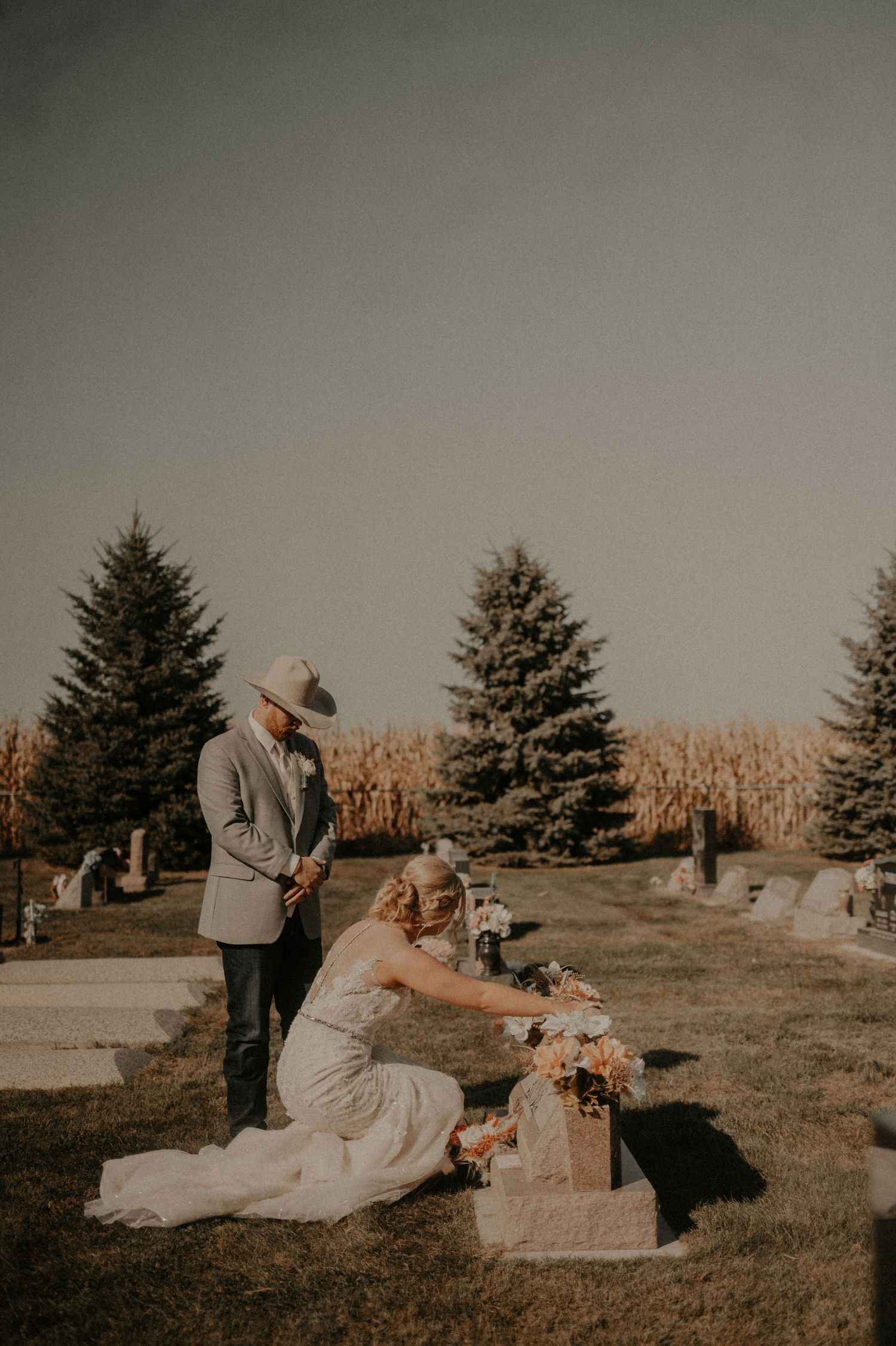 Outdoor cemetery scene with evergreen trees and autumn colors in the background.