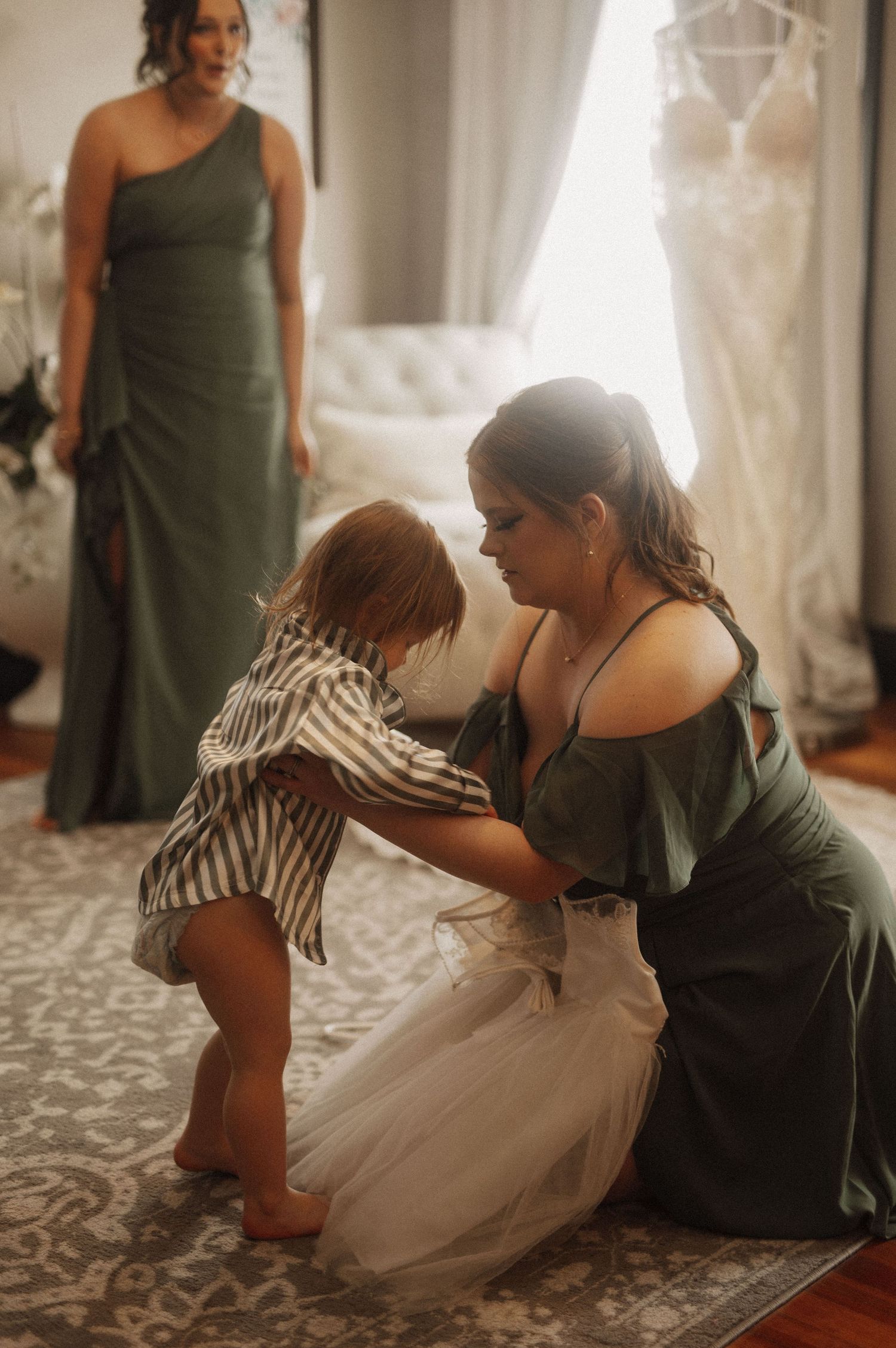 A small child in a white dress plays on the floor during wedding preparations.