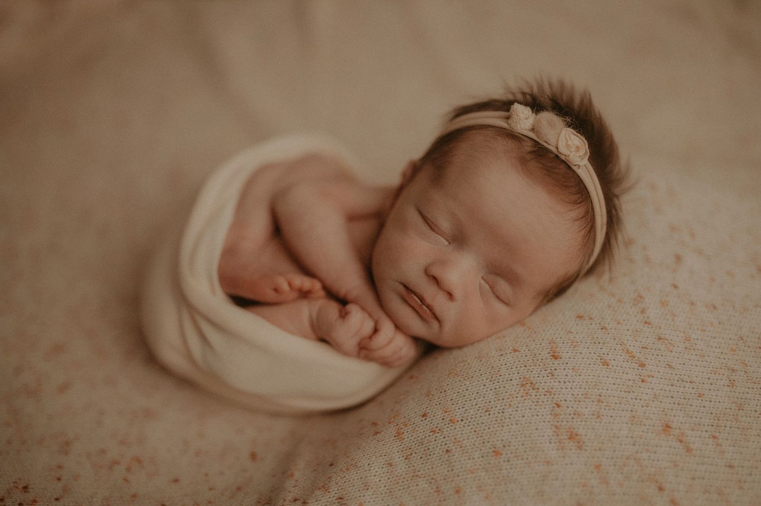 Peaceful newborn photography session featuring soft beige tones and delicate wraps.