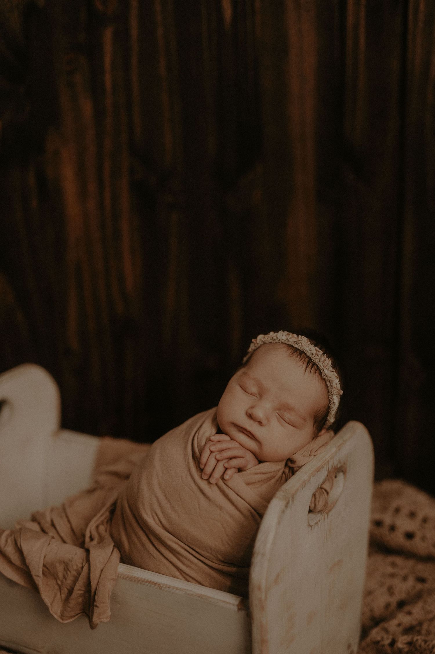 A sleeping infant rests peacefully in sepia tones with a soft blanket.