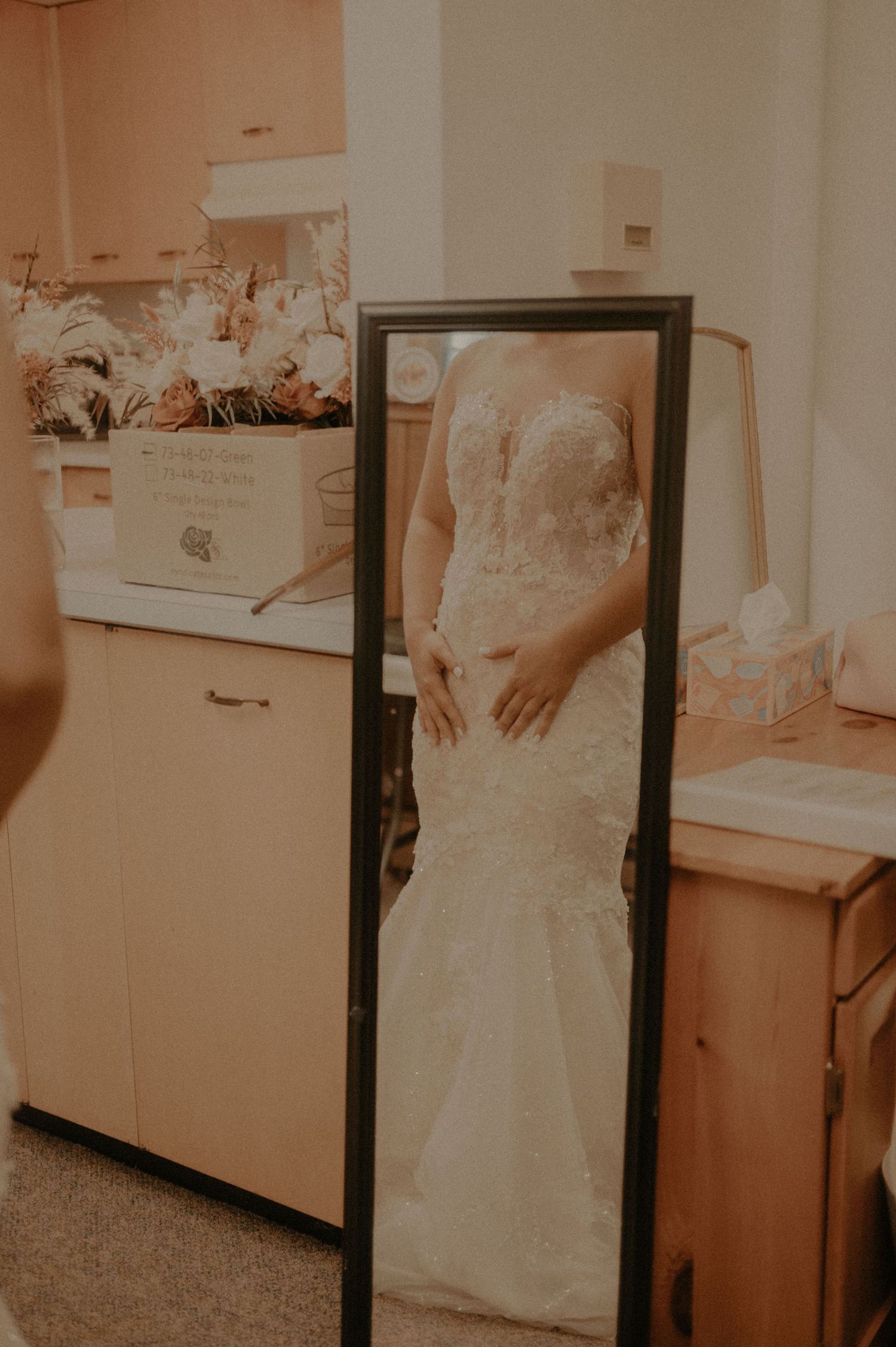 Wedding dress fitting session with a full-length mirror in a dressing room.
