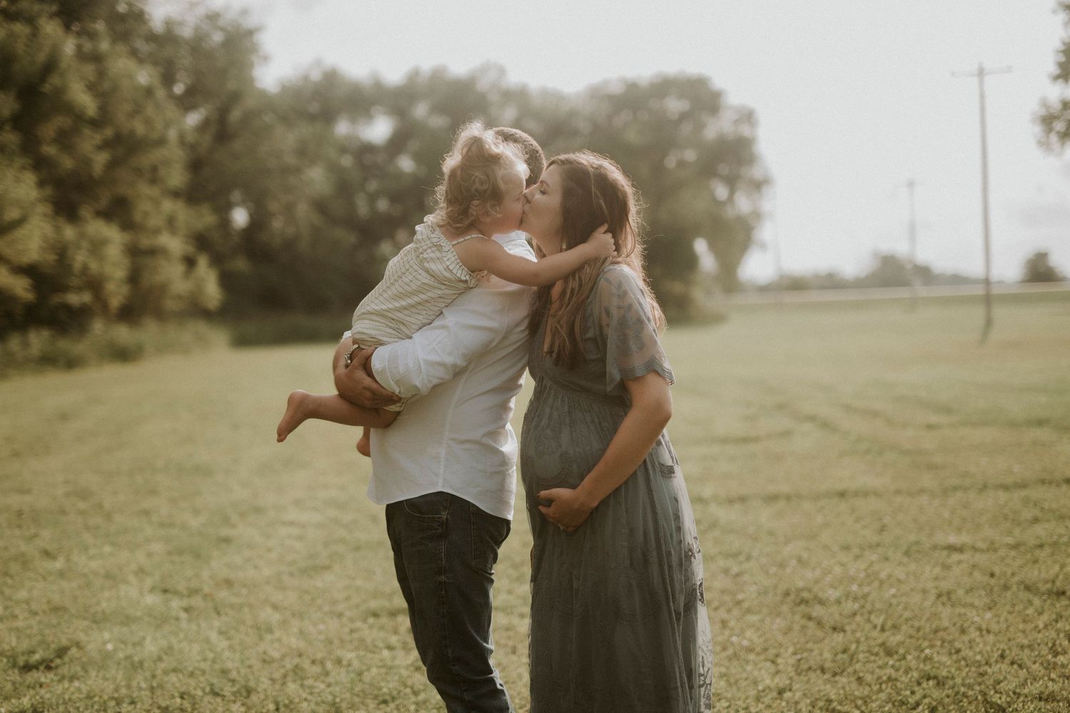 A romantic couple embraces in a sunlit meadow during a warm afternoon photo session.