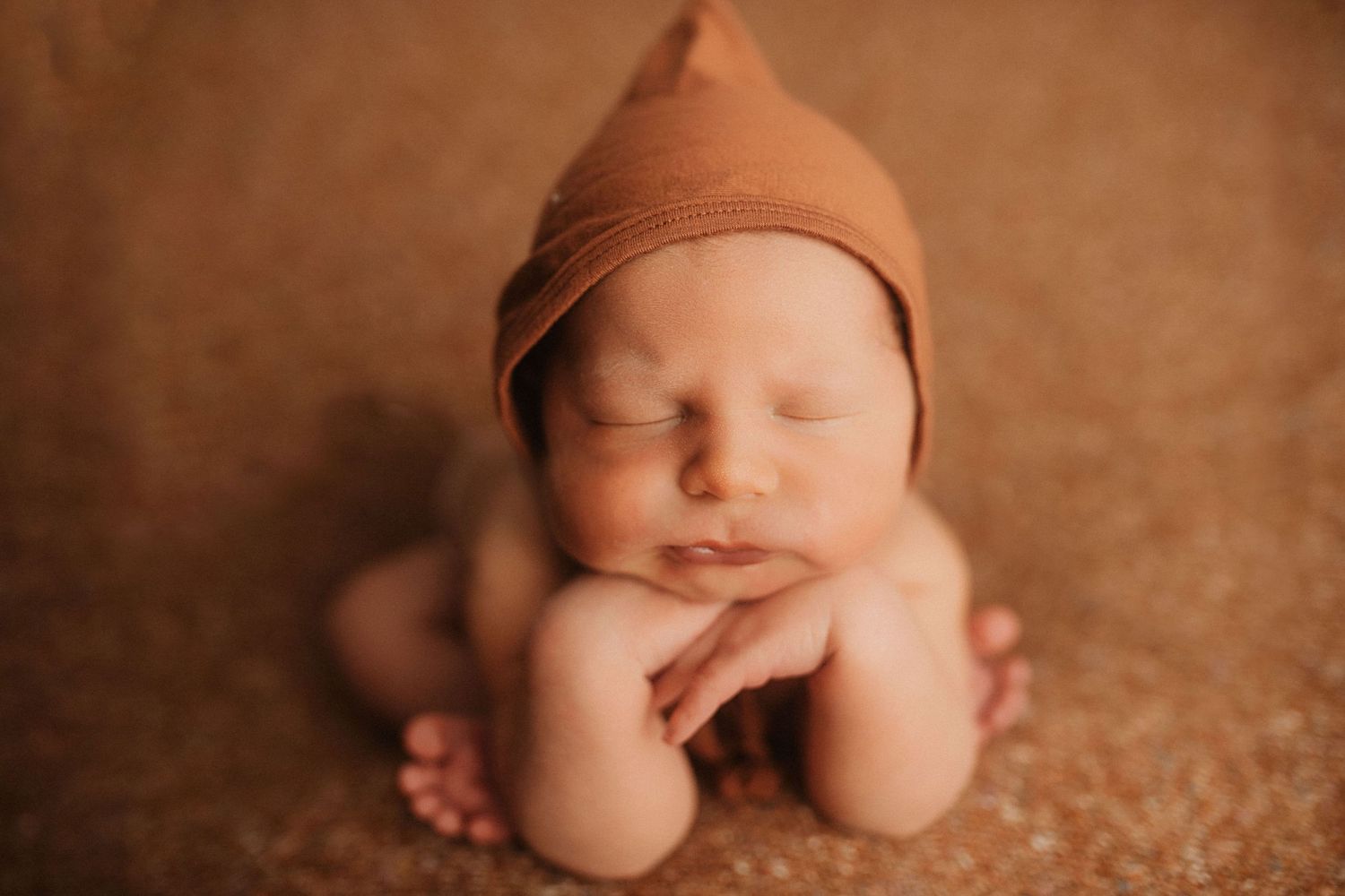 Delicate newborn photography with rustic copper-toned background and soft natural light.