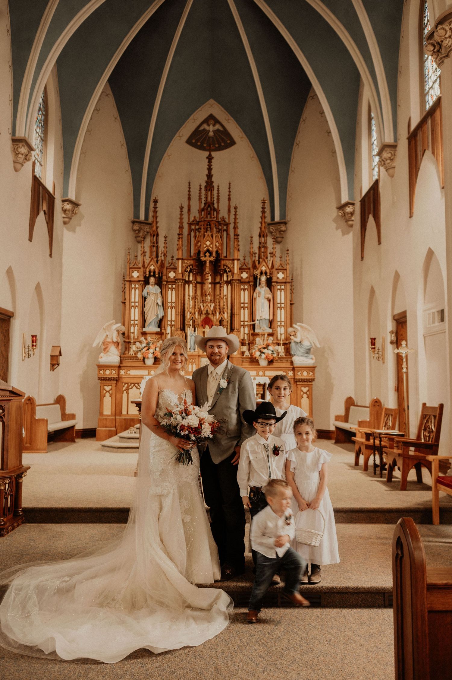 A wedding party poses for formal photos in a traditional church sanctuary.