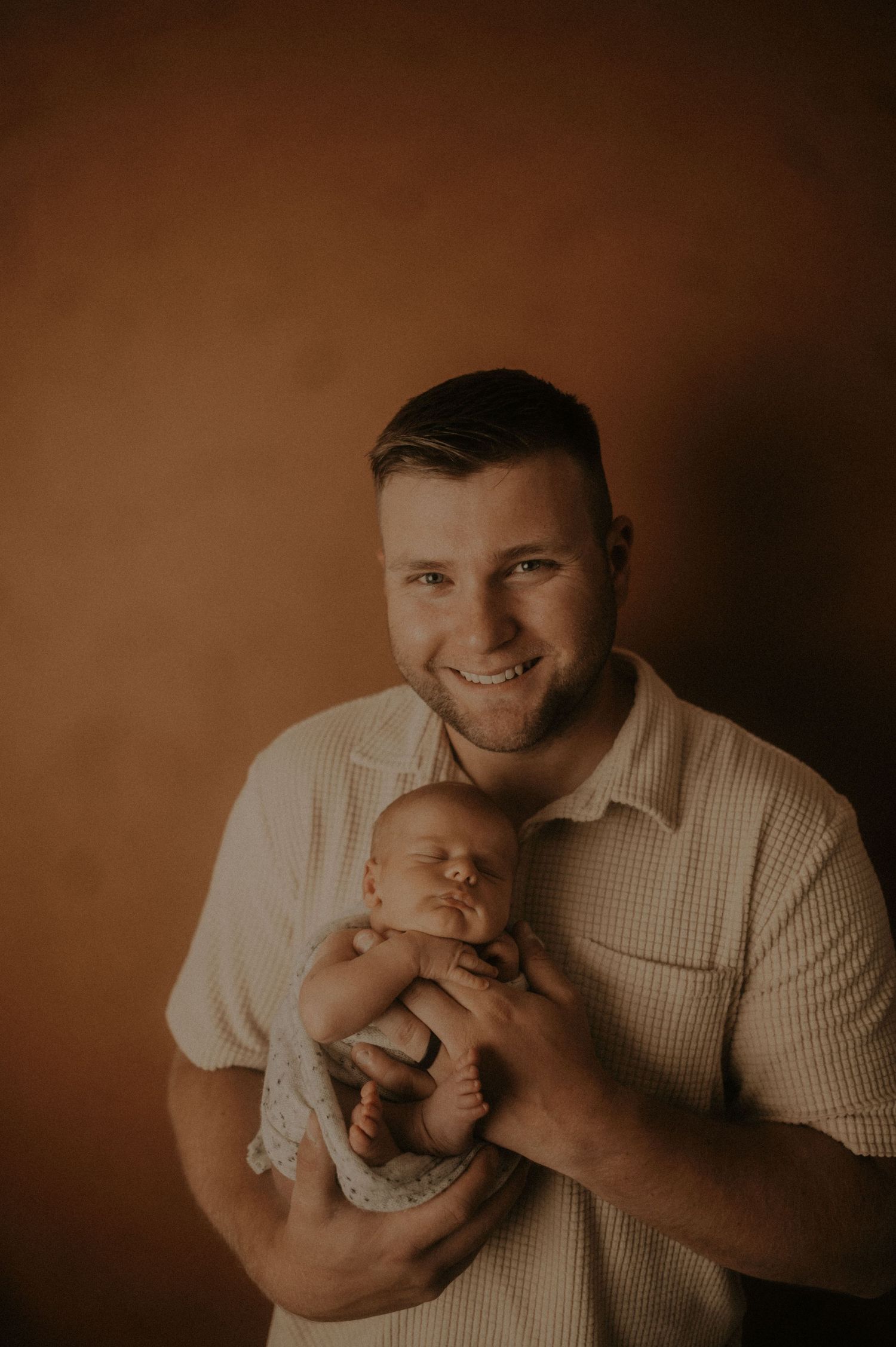 Warm-toned studio portraits capture intimate family moments in sepia lighting.