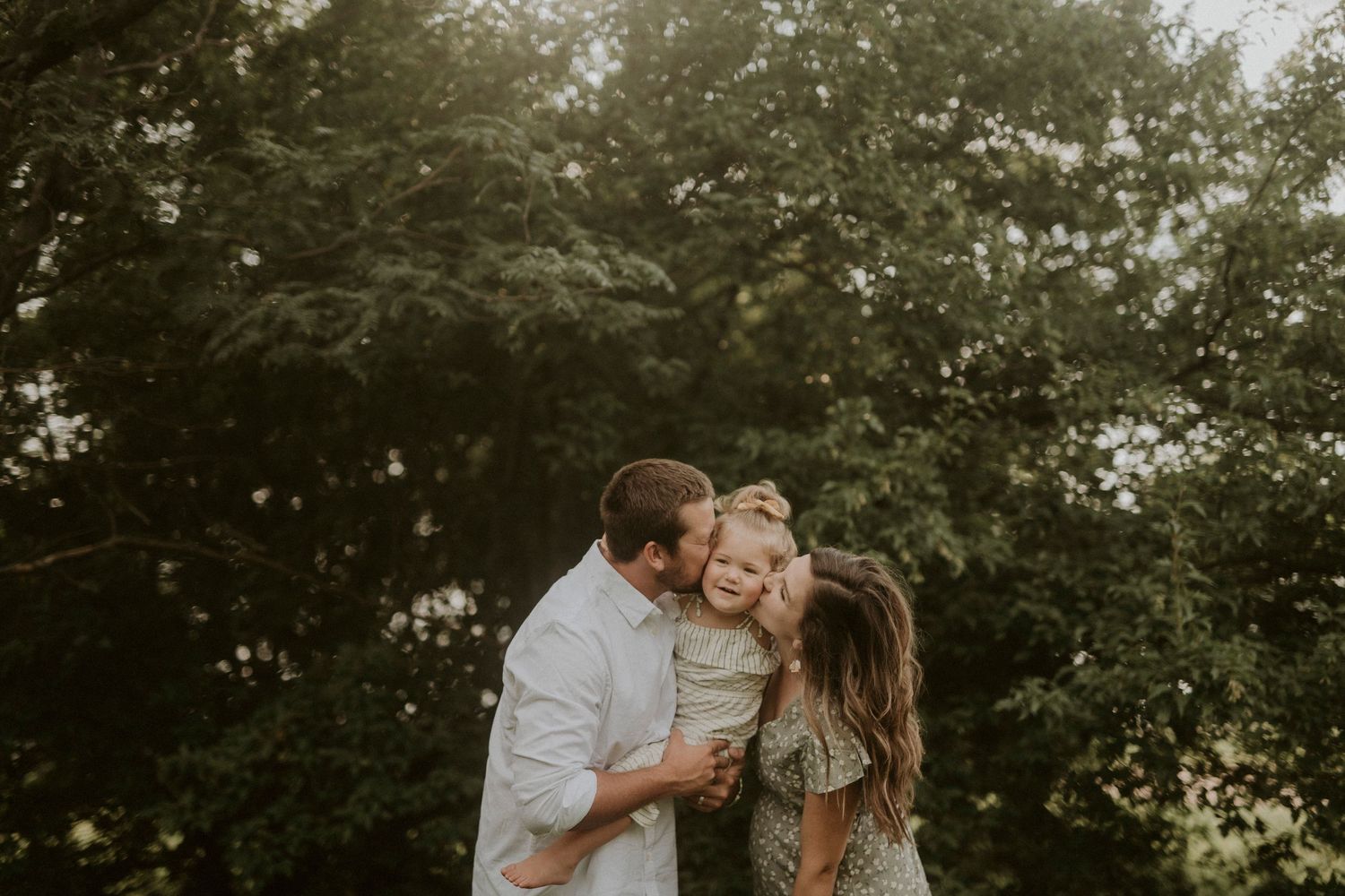 A couple shares an intimate moment together in a lush outdoor garden setting during a romantic photoshoot.
