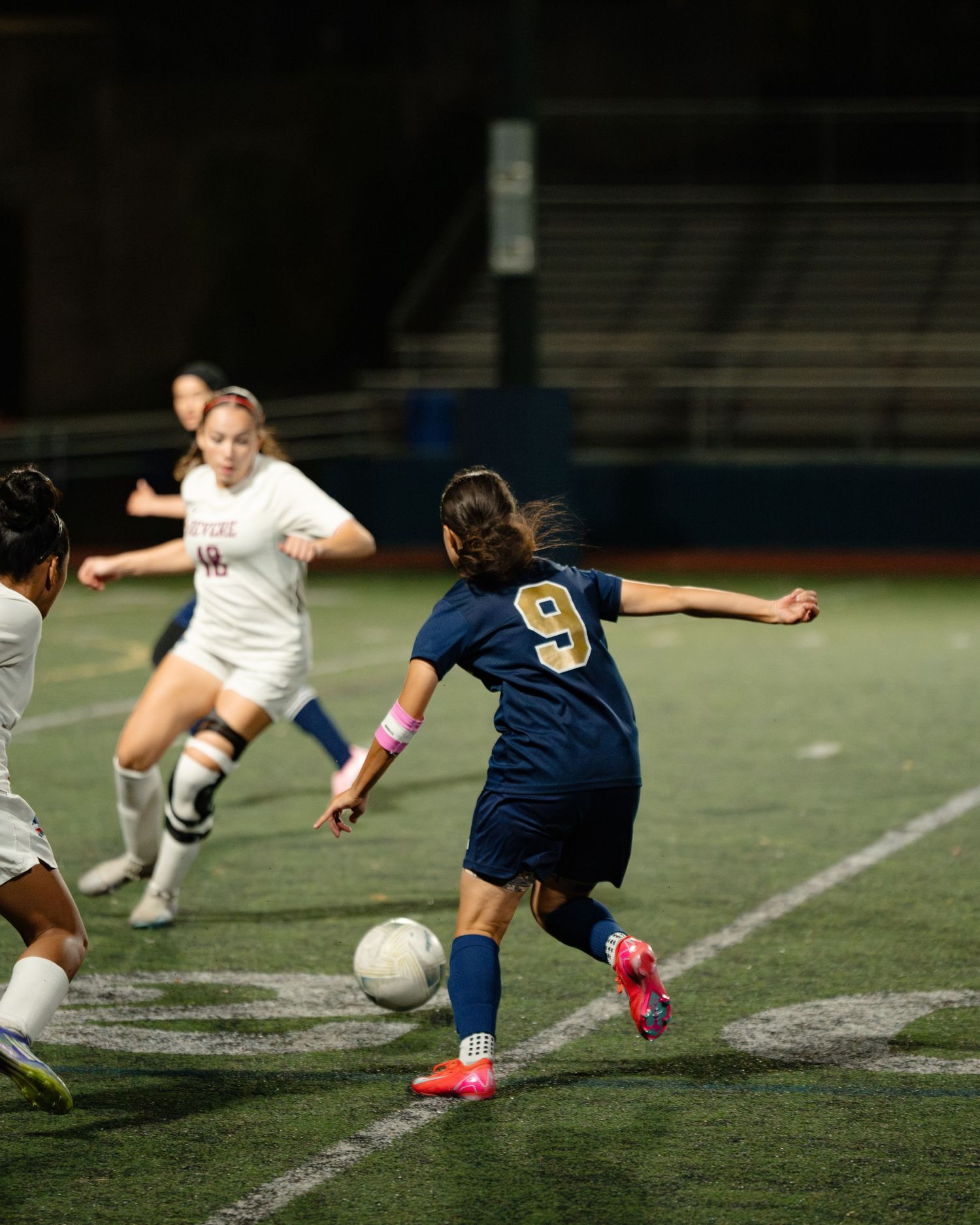 Soccer players compete for possession of the ball during an intense nighttime match on an artificial turf field. Boston MA photographer.