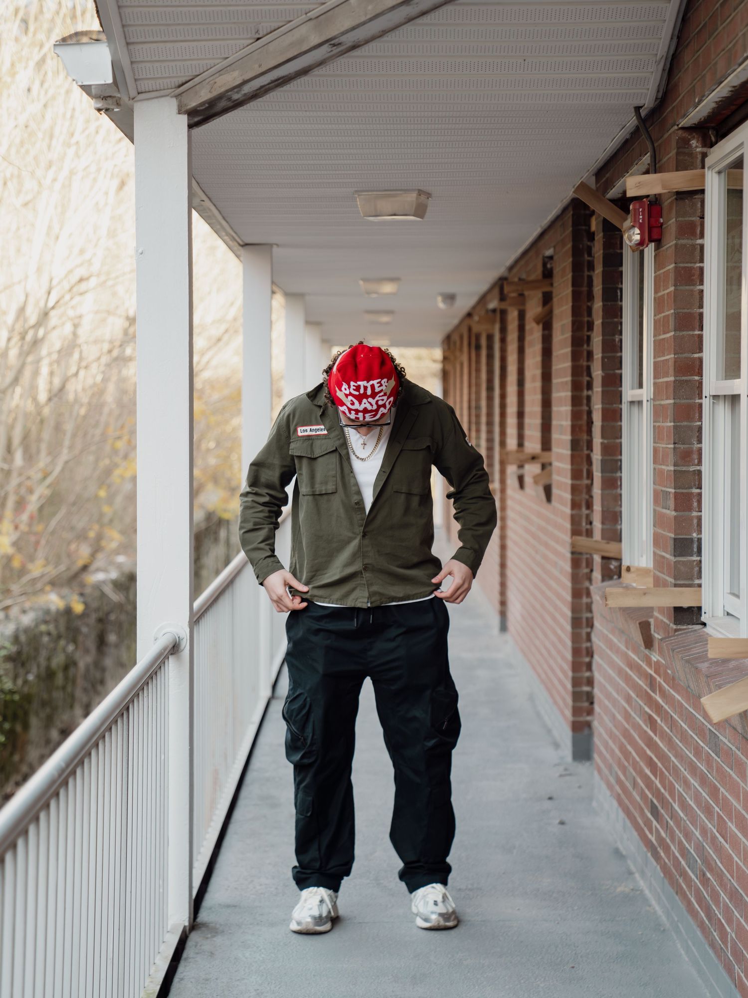 A person in a green sweater and dark pants walking down a covered brick porch. Boston MA photographer, Malden MA & Greater Boston Area.