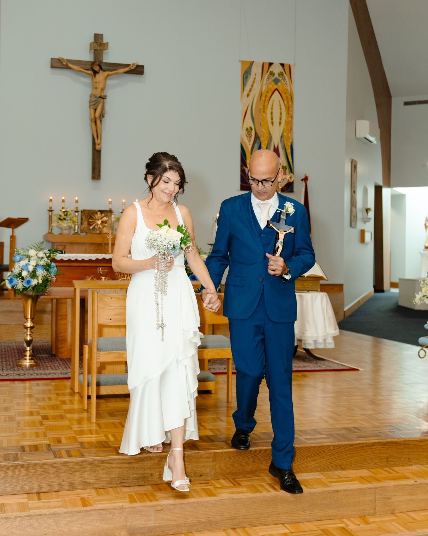 Couple in wedding attire a church floor with wooden panels and religious decor. Boston MA photographer, Malden MA and Greater Boston.