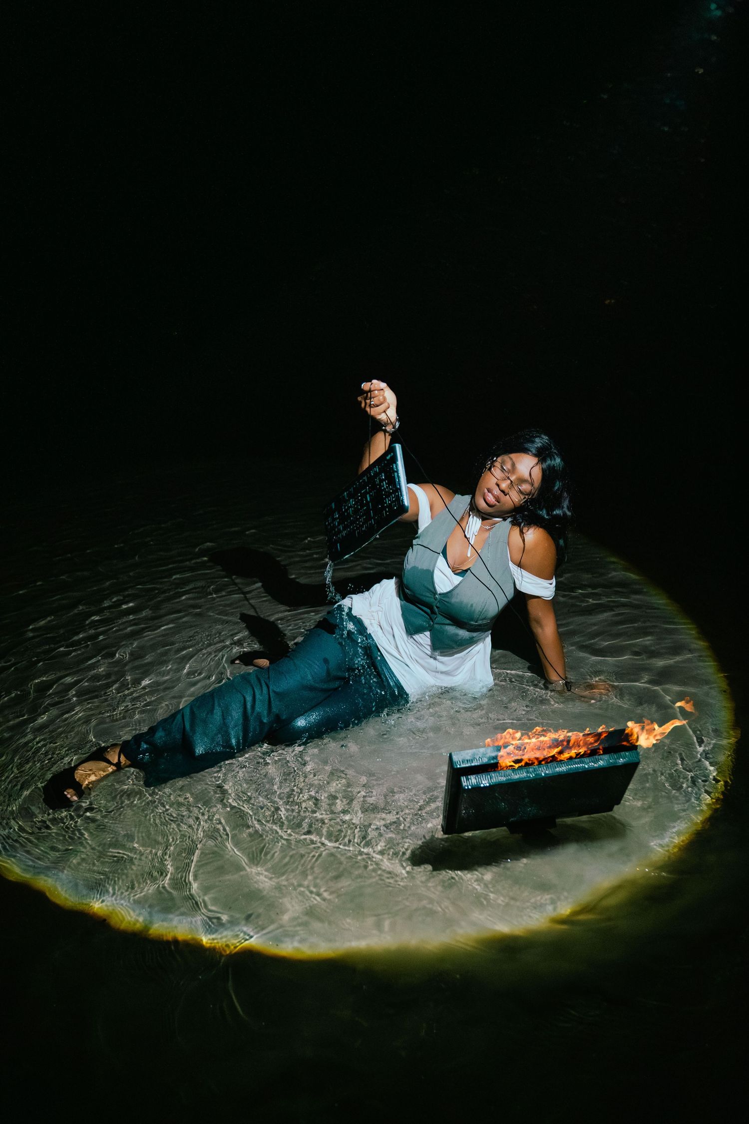 Person in casual attire poses dramatically on the ground next to a pizza box in a dark setting with dramatic lighting. Boston photographer.