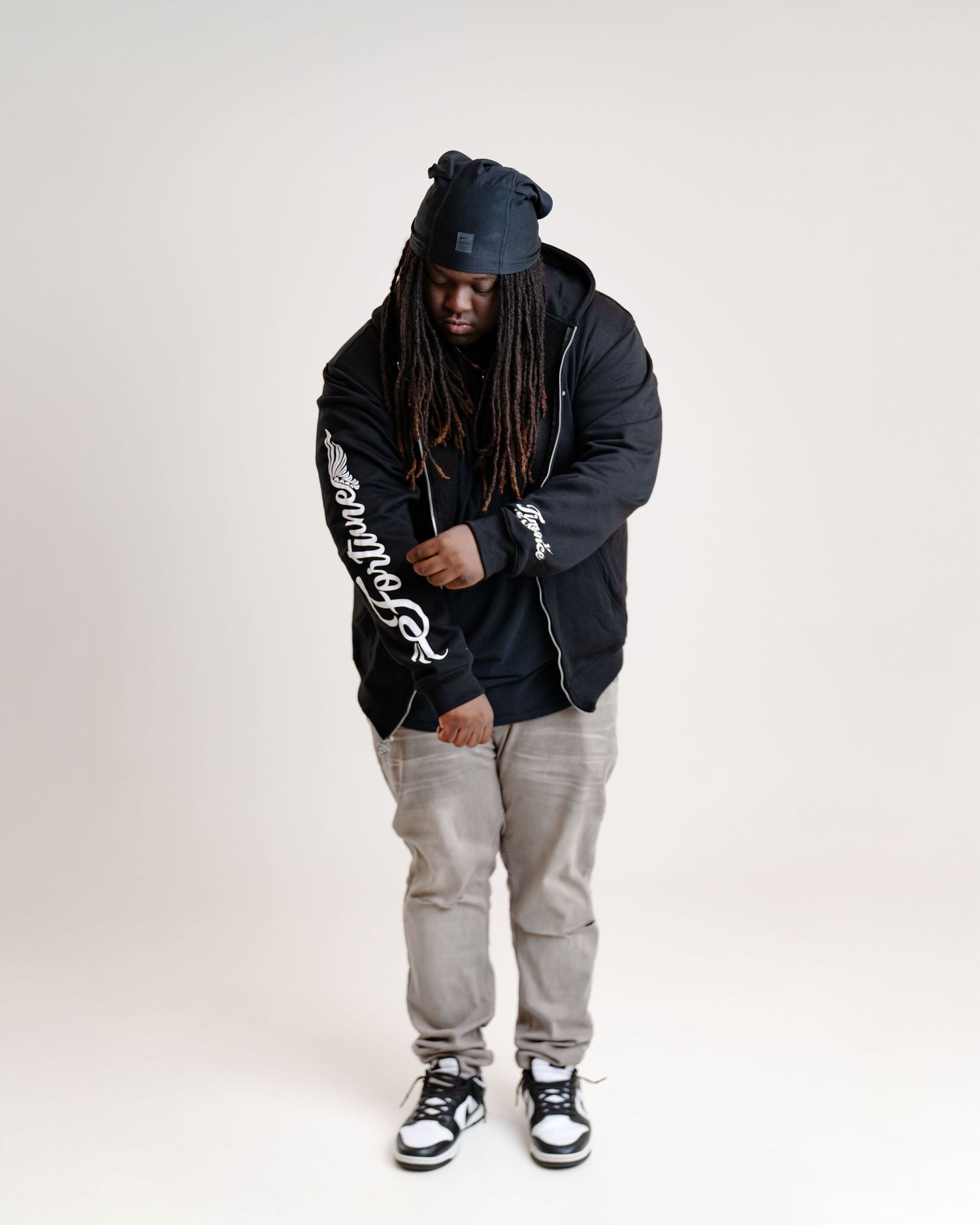 A person in a dark hoodie and gray sweatpants strikes different casual poses against a white backdrop. Boston MA photographer, Malden MA.