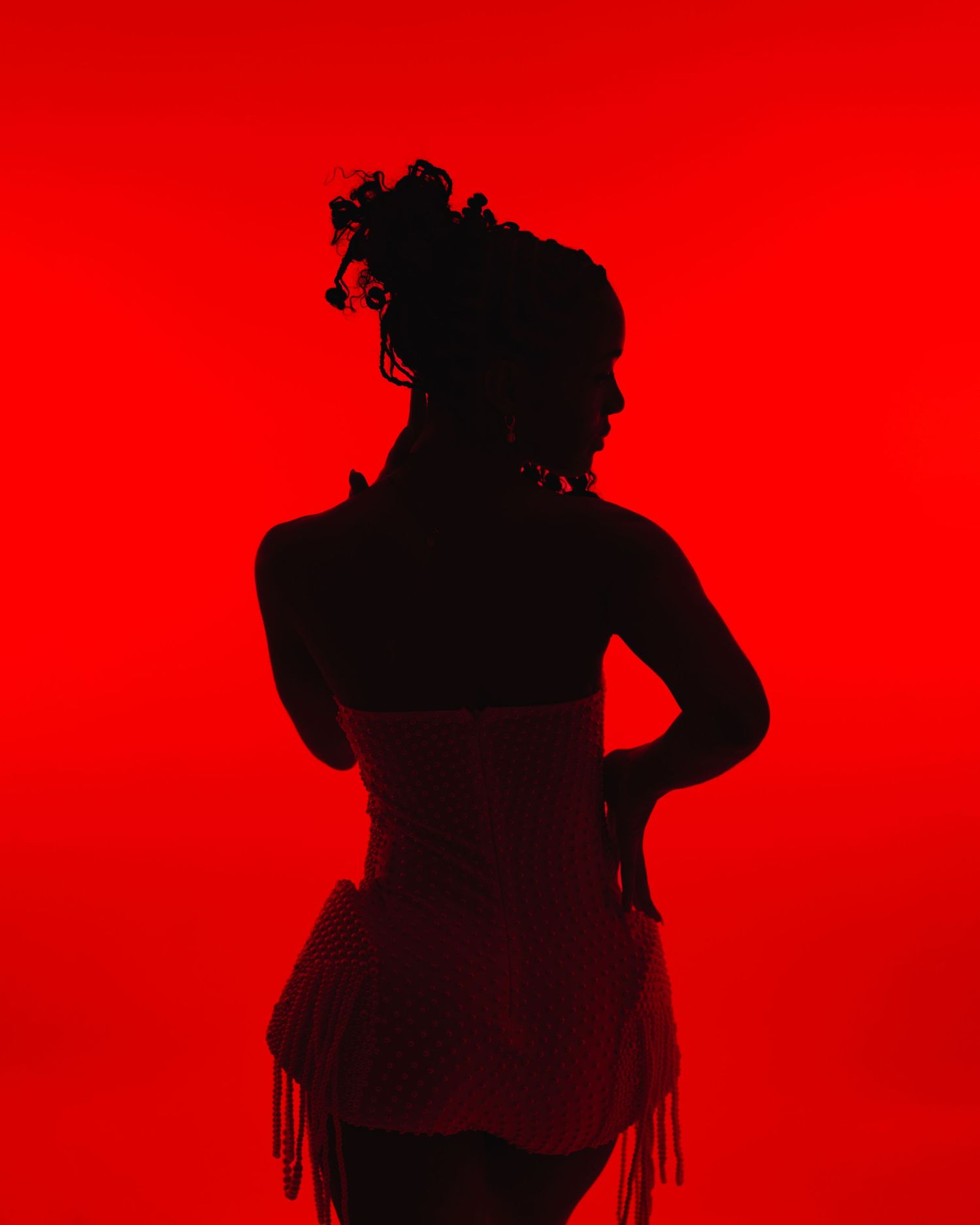 Silhouetted figure in motion against a vibrant red background creates a striking contrast in this artistic portrait. Boston MA photographer.