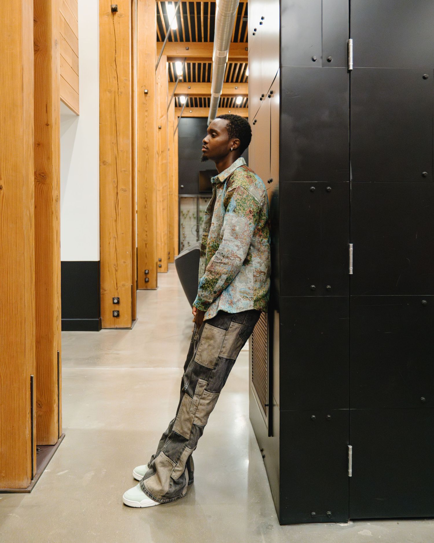 Fashion model lean against dark lockers in a hallway with wooden beams and white walls. Boston MA photographer, Malden MA and Greater Boston